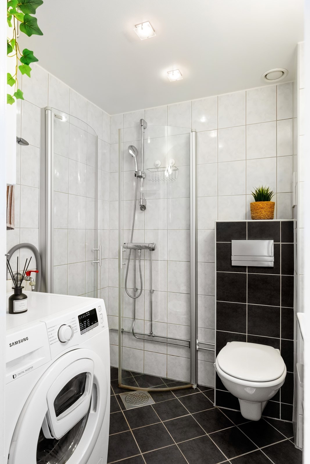 Badet består av servant med skap, speil og belysning, veggmontert toalett og dusjhjørne med vegg/dør i herdet glass. Galleribilde