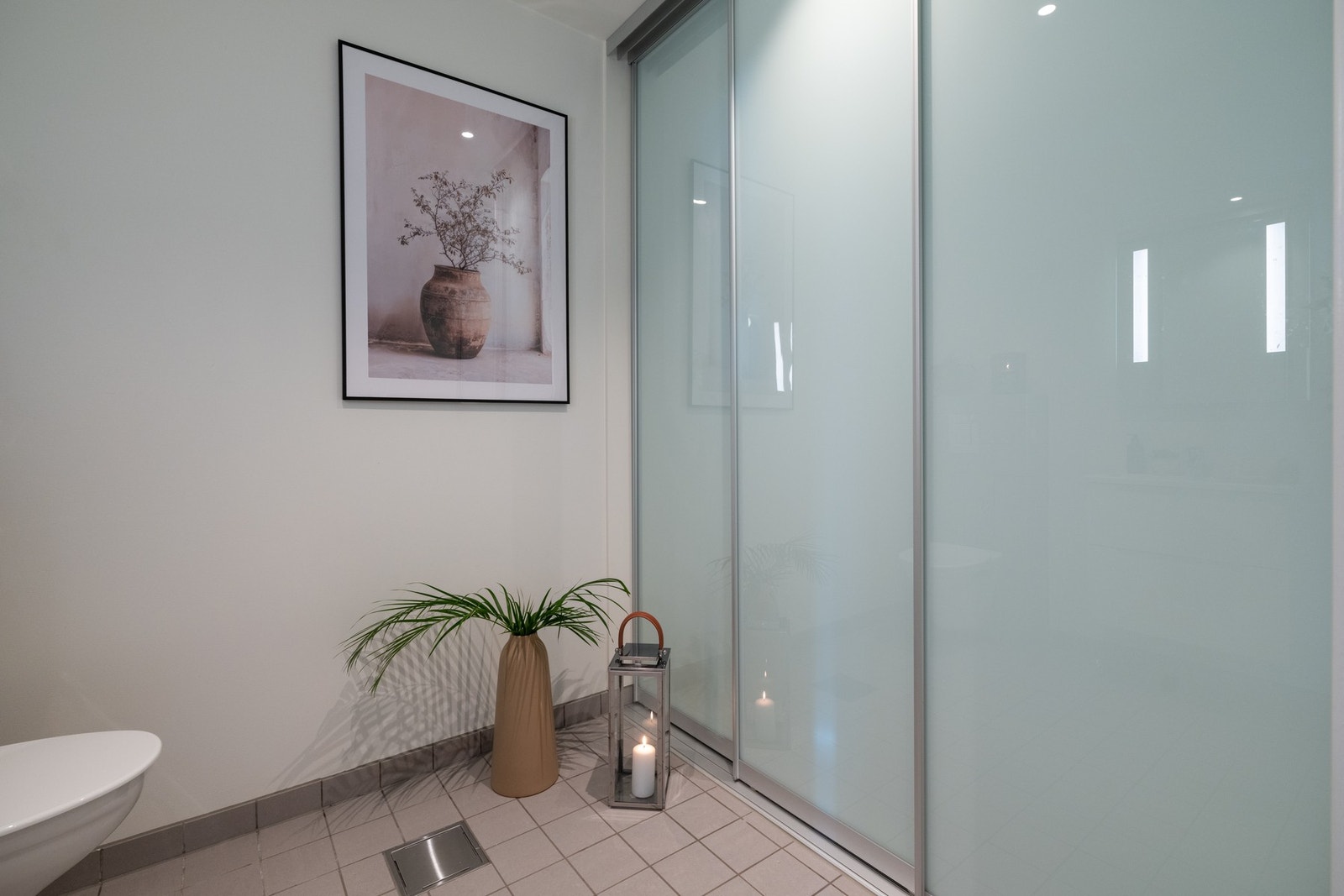 Rommet er innredet med servant på underskuffer, speil med integrert belysning og vegghengt toalett. Galleribilde