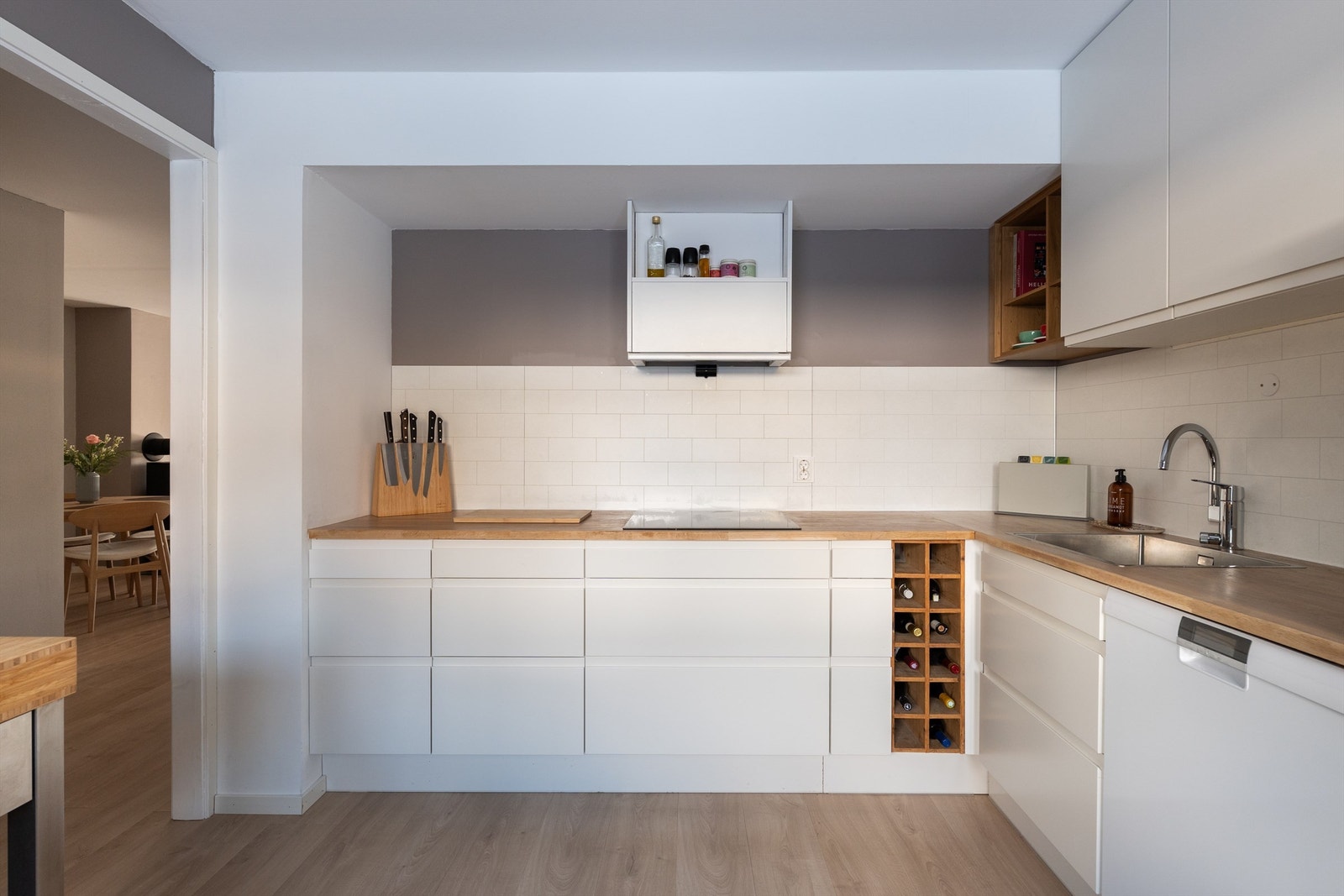 Moderne kjøkken i L-løsning med integrert stekeovn, koketopp og oppvaskmaskin. Galleribilde