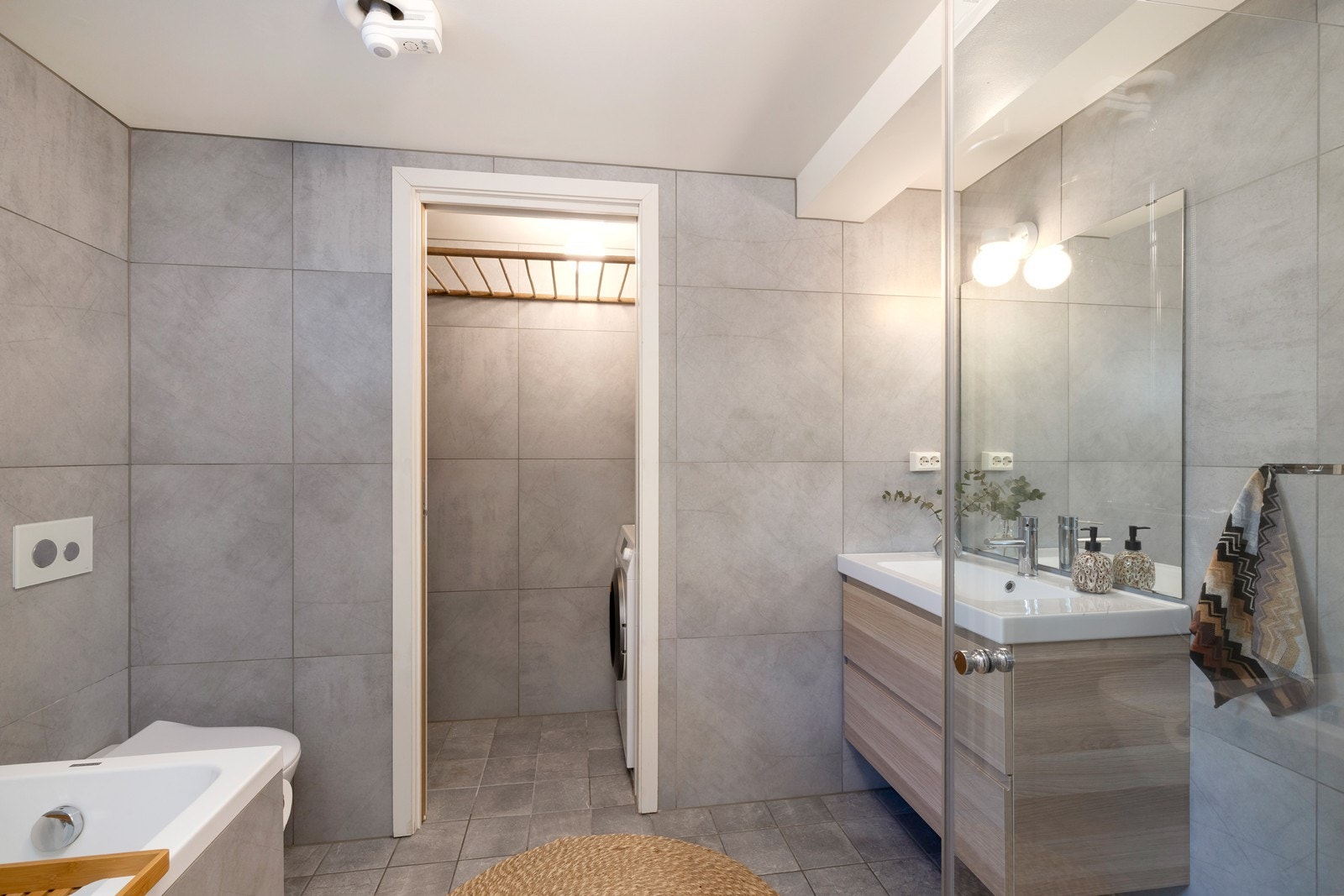 Badet er utstyrt med badekar, vegghengt toalett, servant og dusjhjørne. Herfra har du også videre adkomst til vaskerom. Vaskerommet kan lukkes med skyvedør i tre. Galleribilde