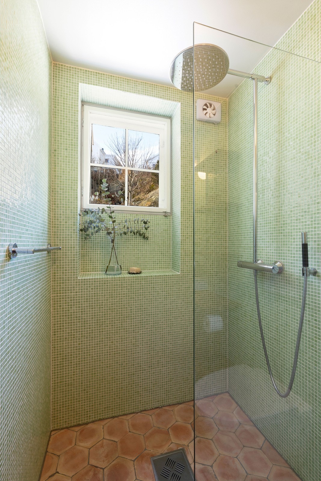 Badet er helfliset med italienske terracotta fliser på gulv og grønn mosaikk på vegger. Legg også merke til "sjampo-hylle" ved vindu. Galleribilde