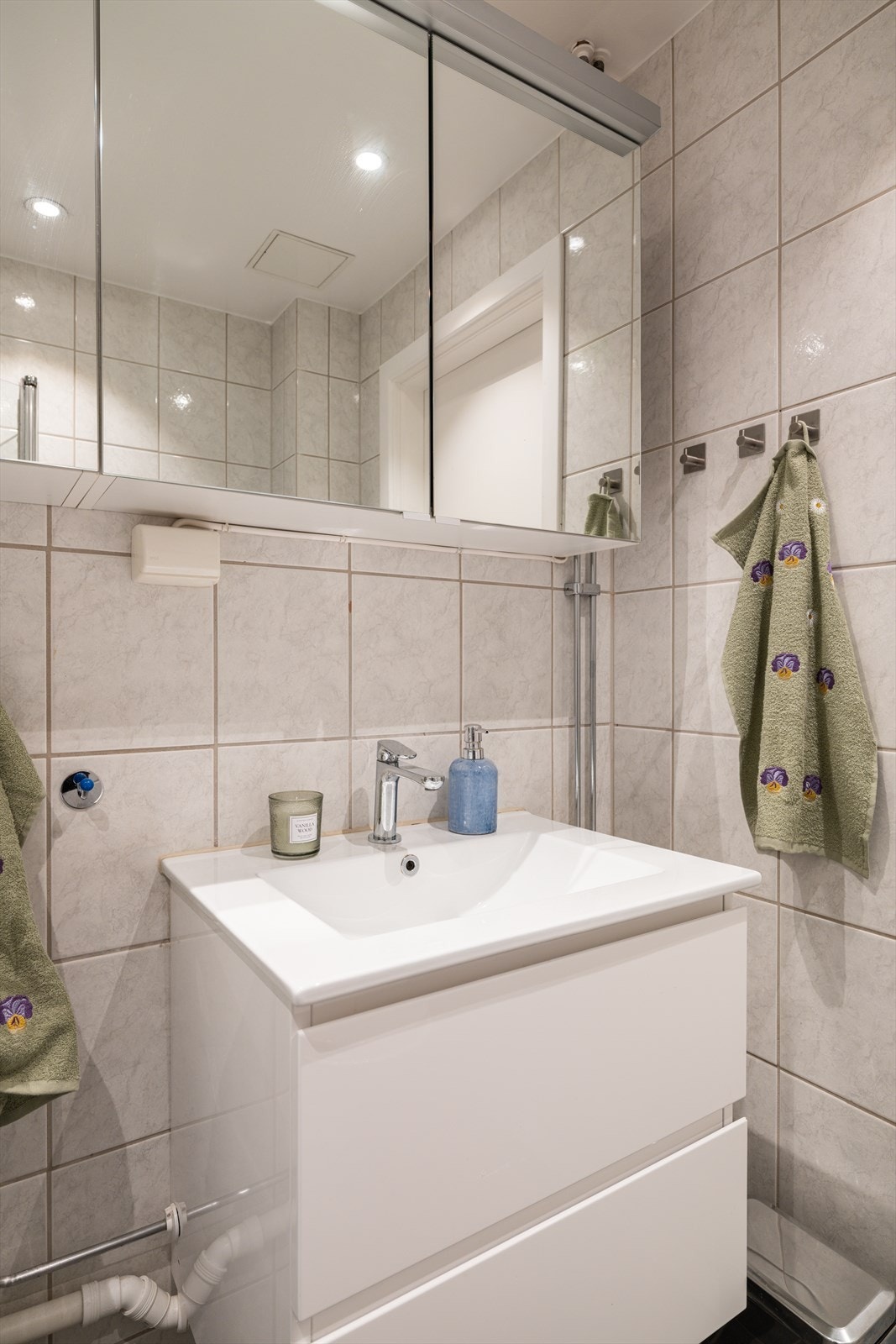 Badet består av vask, frittstående wc, dusjhjørne med svingbar glass dører og opplegg for vaskemaskin. Galleribilde