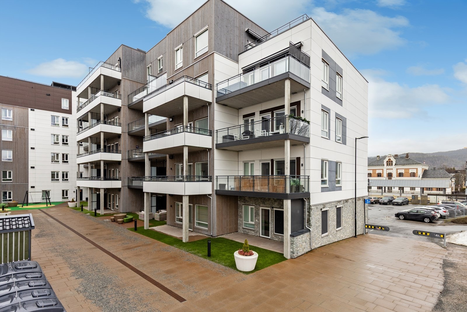 Bygget fra 2022 har en moderne fasade med en kombinasjon av trepanel og plater. Felles gårdsrom med sittegrupper. Galleribilde