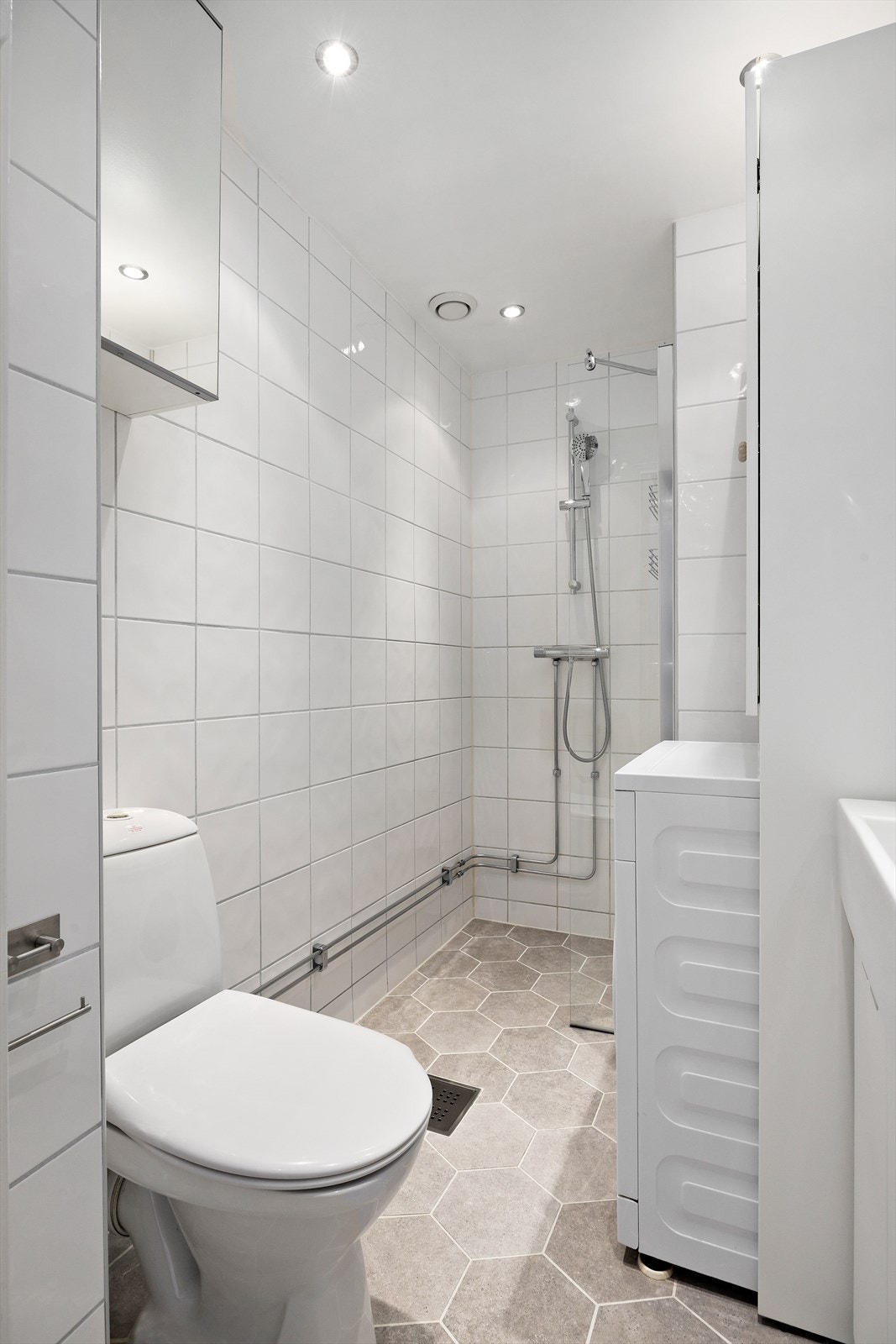 Badet består av flislagte overflater og er utstyrt med dusj, servant og opplegg for vaskemaskin. Galleribilde