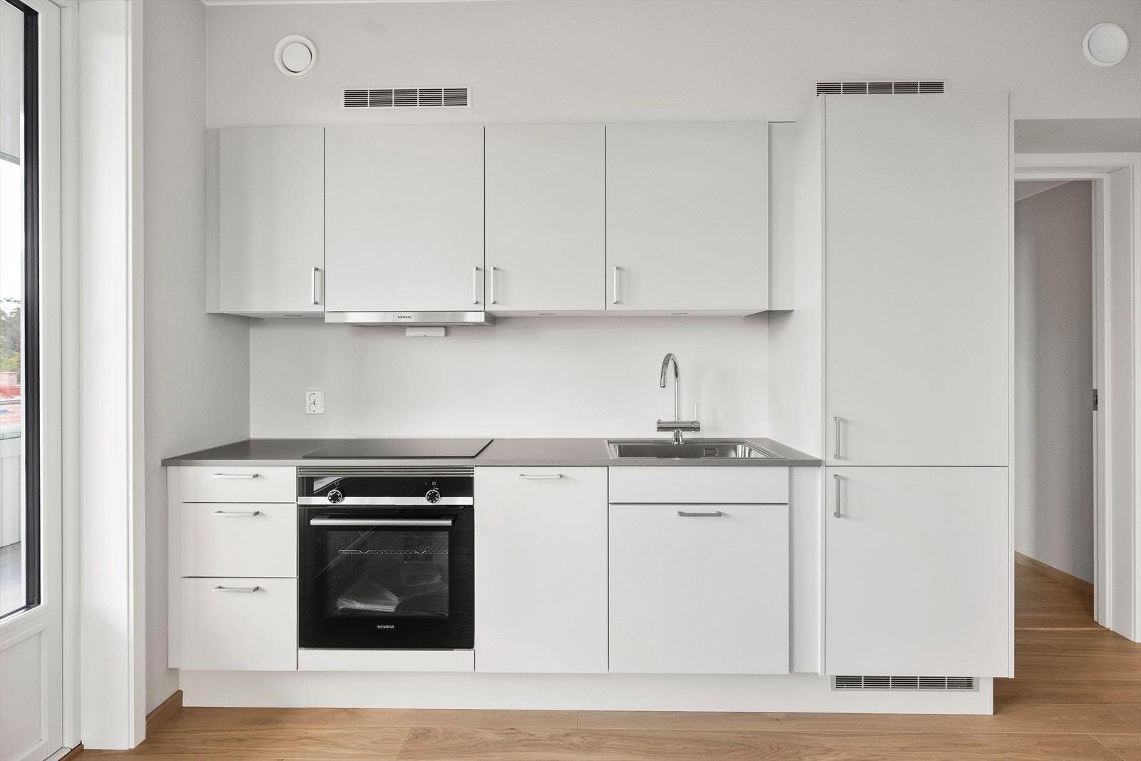 Over koketopp leveres kjøkkenventilator med kullfilter. Kjøkkenet er utstyrt med integrerte hvitevarer som stekeovn, induksjonstopp, oppvaskmaskin og kombiskap (kjøl/frys) fra Siemens Galleribilde