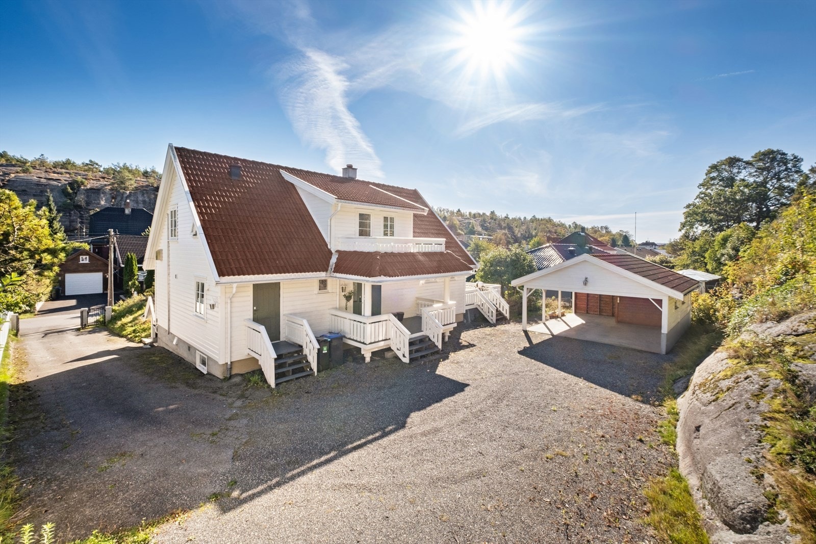 Gruset oppkjørsel og gårdsplass med dobbel carport og gode parkeringsmuligheter. Galleribilde
