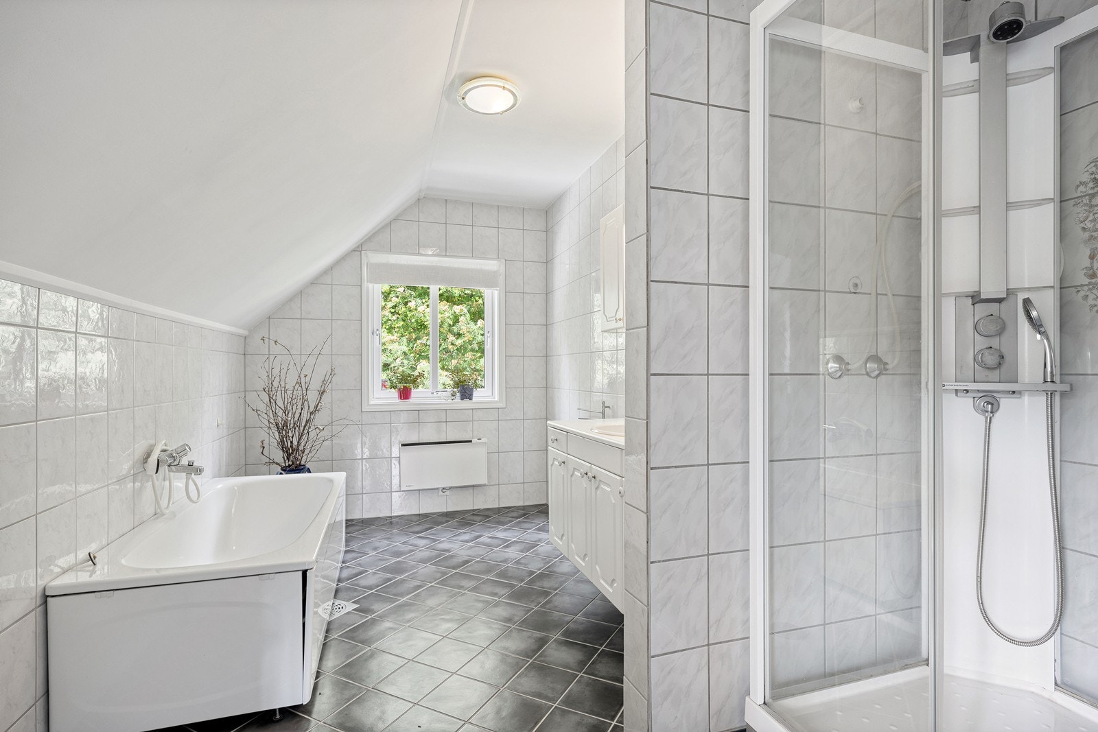 Badet er stort og utstyrt med badekar, dusjkabinett og toalett. Galleribilde
