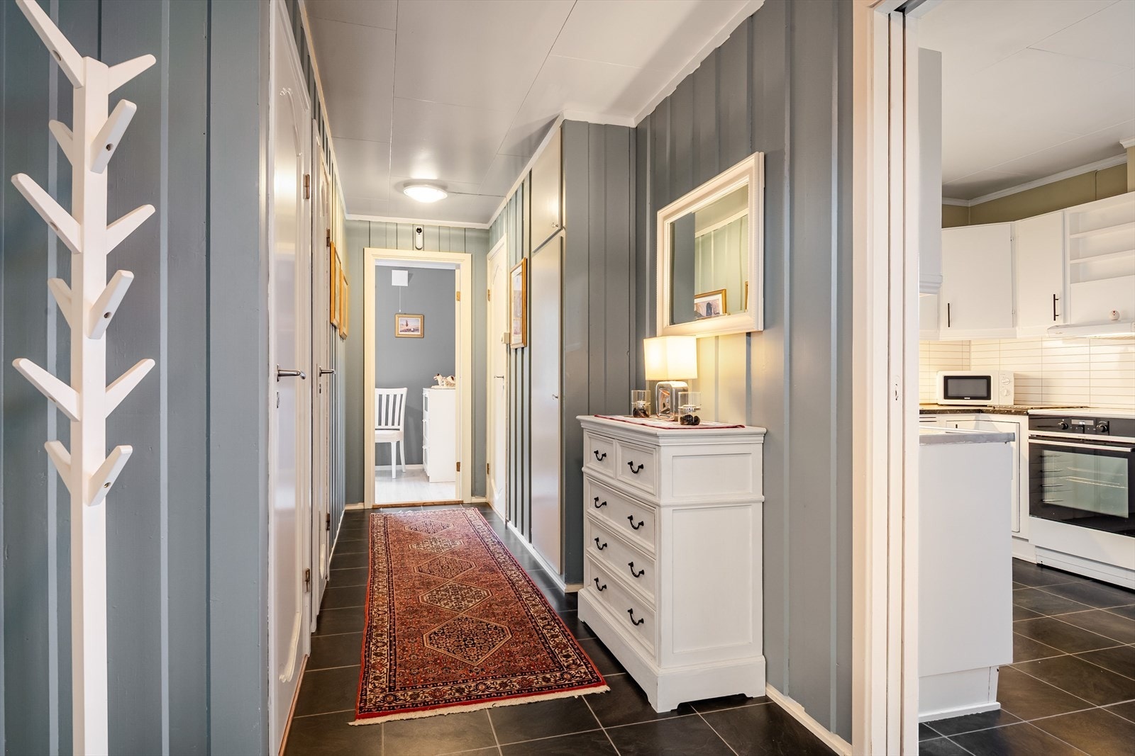 Gangen har flislagt gulv og panelvegger malt i en lun blåtone. Galleribilde