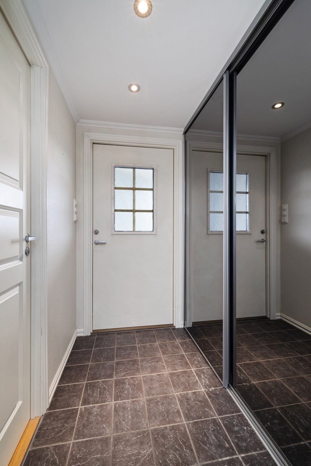 Entréen har flislagt gulv og god plass til oppbevaring i en stor skyvedørsgarderobe. Galleribilde