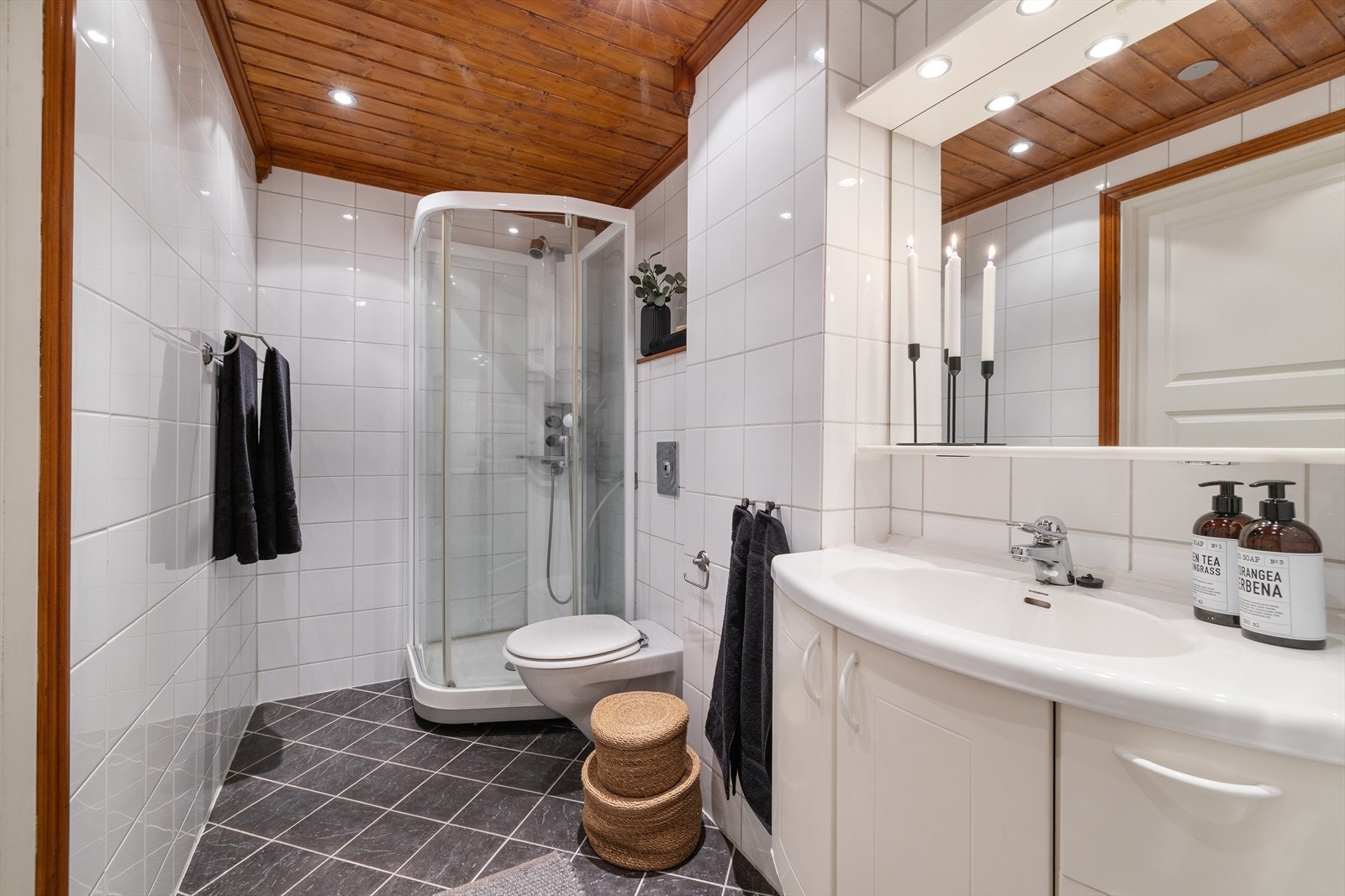 Badet har flislagte overflater, vegghengt toalett, dusjkabinett og elektrisk gulvvarme. Galleribilde