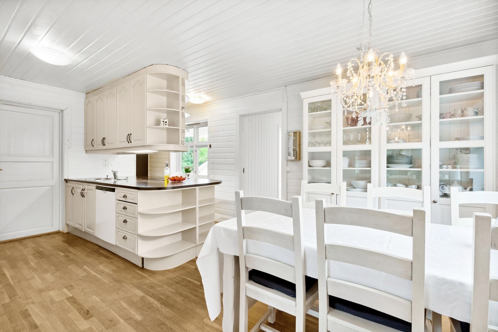 Pen innredningen med malte profilerte fronter, takhøye overskap og en laminat benkeplate med nedfelt kjøkkenkum og platetopp. Galleribilde