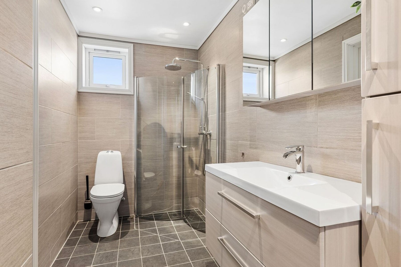 Badet har godt med oppbevaringsplass i skuffer og skap. Downlights i himlingen gir godt med lys i rommet, samt et lite vindu. Galleribilde