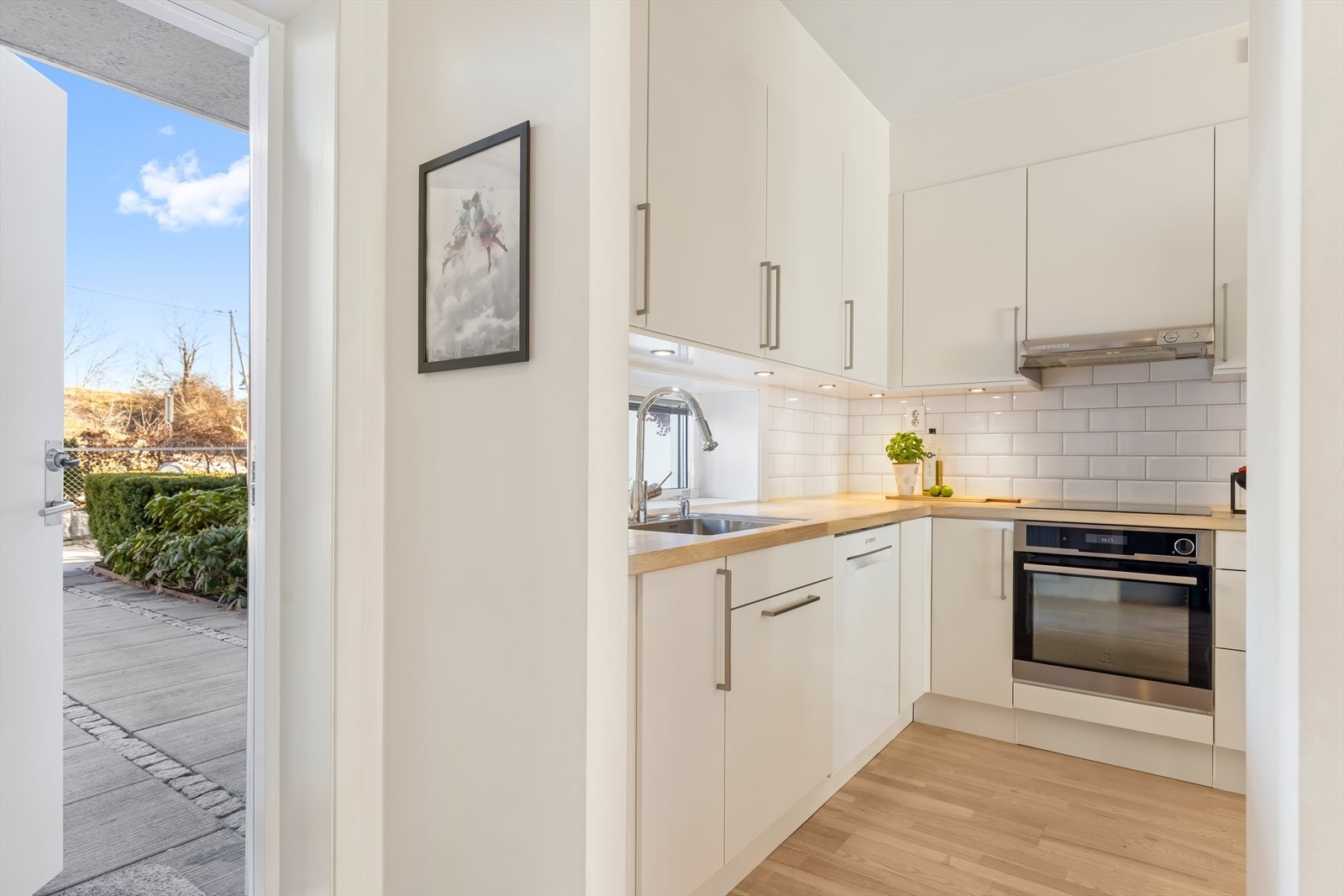 Kjøkkenet fremstår praktisk og tidsriktig, med integrert induksjonstopp, stekeovn og opplegg for oppvaskmaskin. Galleribilde