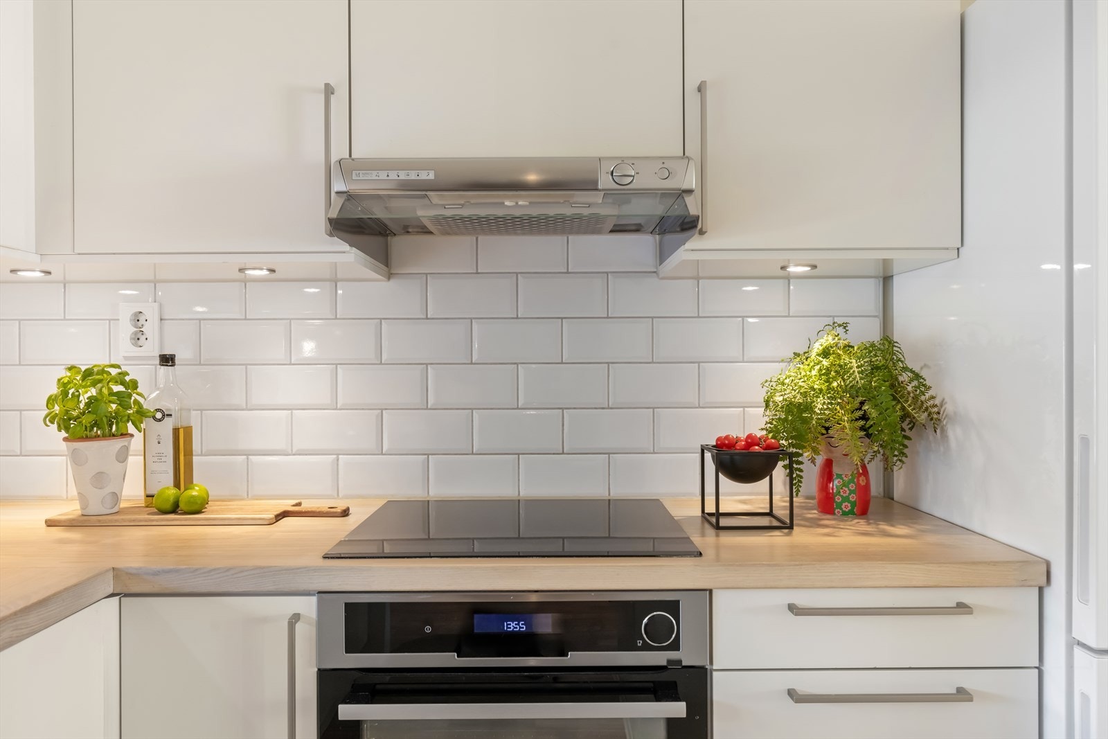 Fliser mellom skapene og ventilator over koketoppen gir et funksjonelt og gjennomført uttrykk. Galleribilde