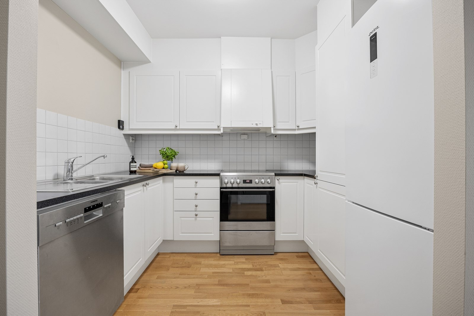 Innredningen har hvite, profilerte fronter og laminatbenkeplate med dobbel oppvaskkum. Galleribilde