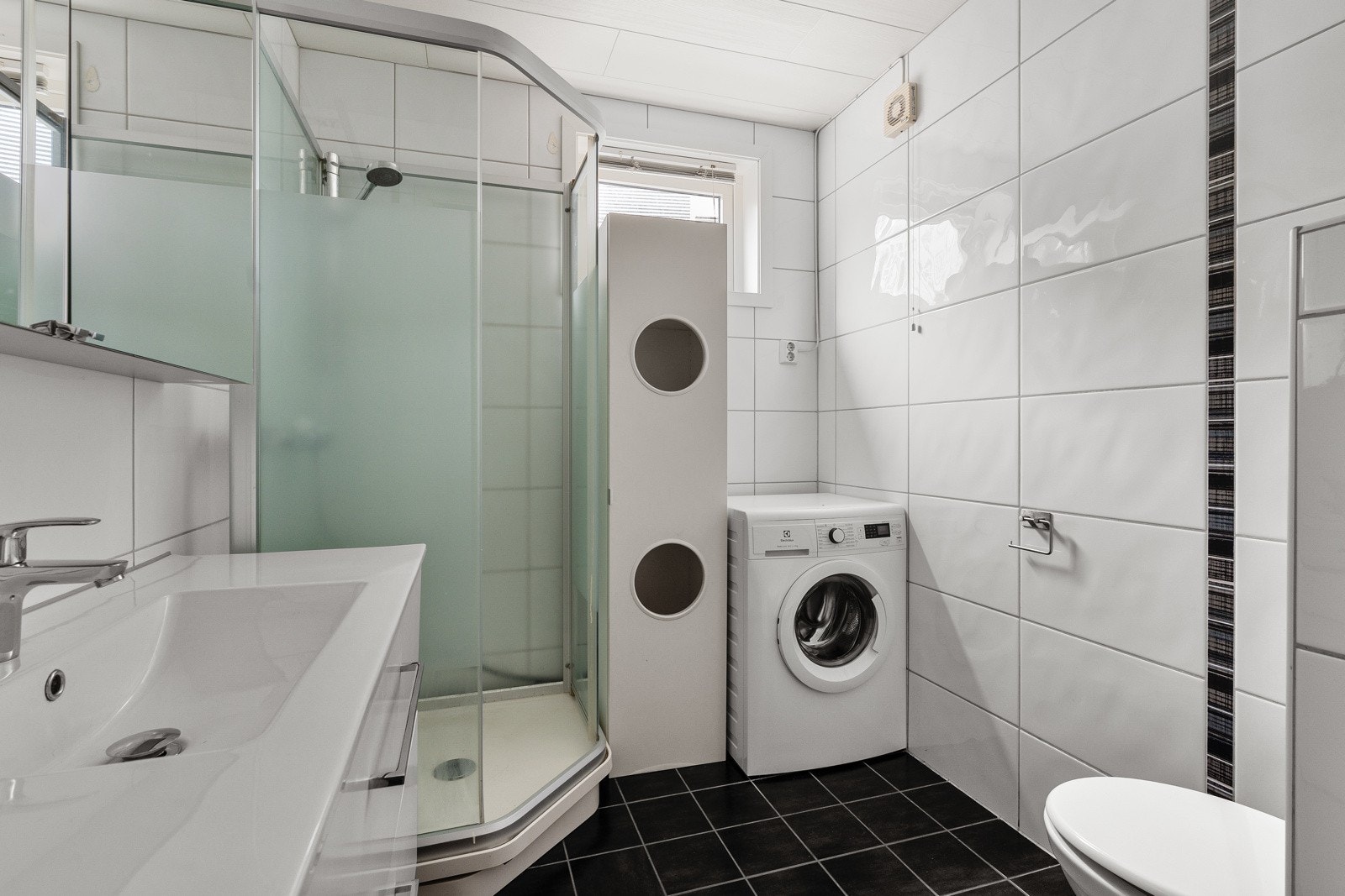 Flislagt bad med dusjkabinett og skapplass.