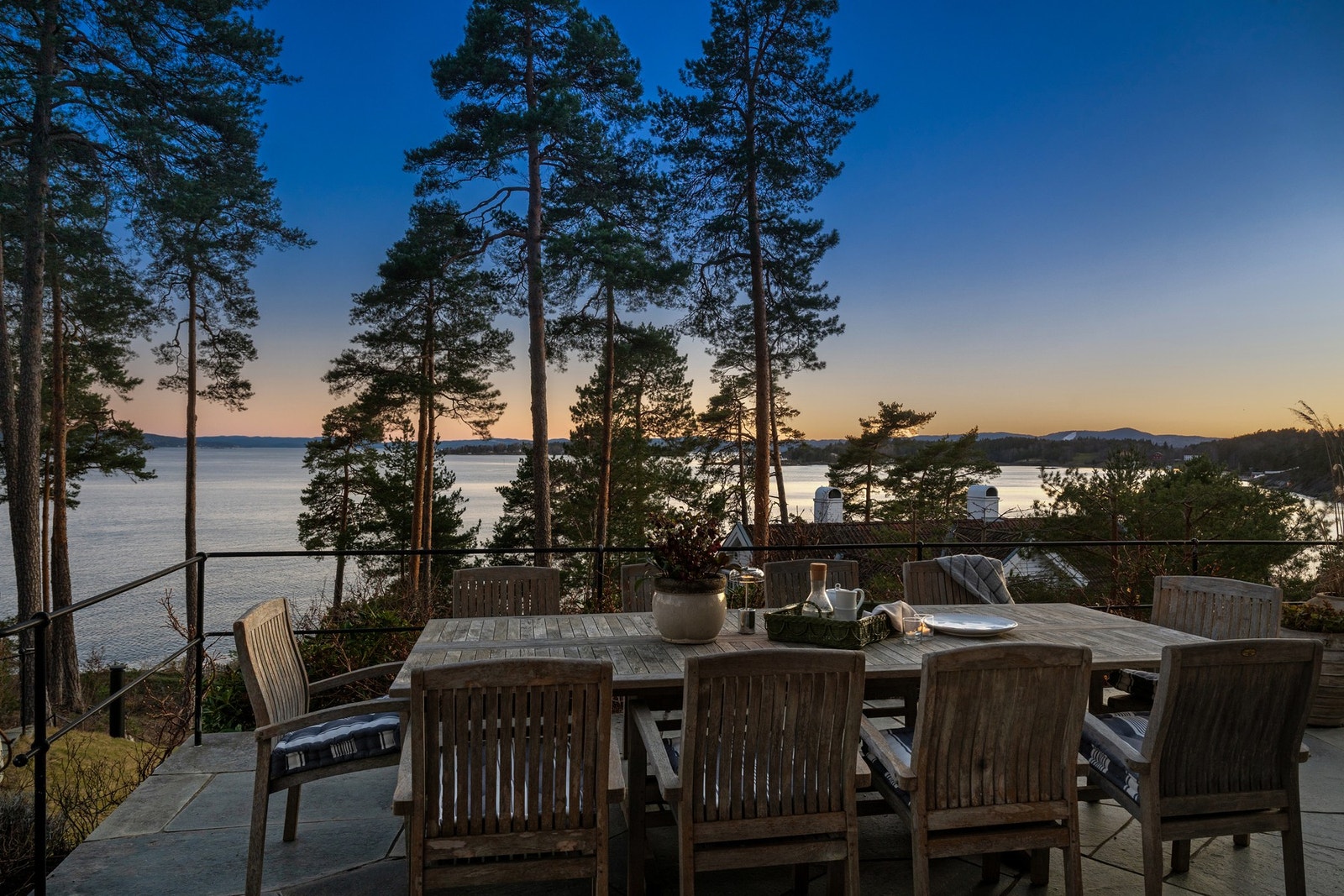 En innbydende uteplass omgitt av natur og med flott utsikt over sjøen i solnedgangen. Galleribilde