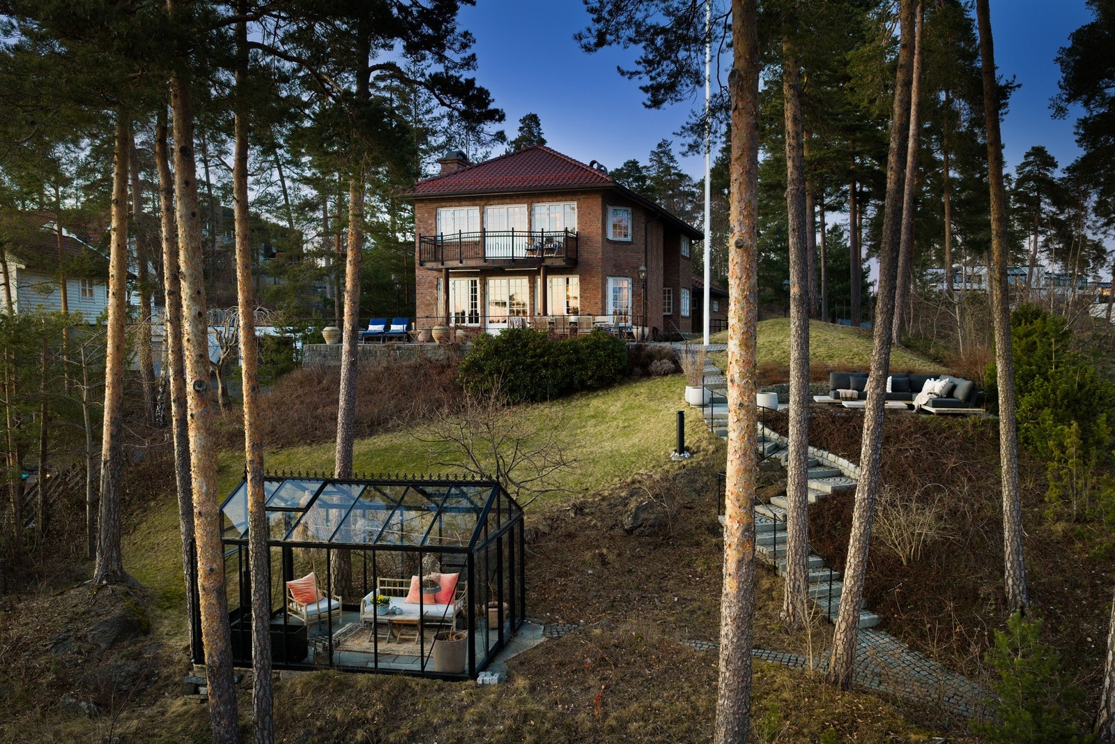 Tomten er pent opparbeidet med flere hyggelige uteplasser, terrasseområder og et sjarmerende drivhus som gir gode muligheter for både avslapning og sosiale sammenkomster i naturskjønne omgivelser. Galleribilde