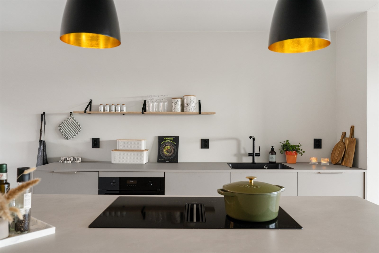 Påkostet kjøkken med steinplate på kjøkkenøy og platetopp med innfelt avtrekk. Galleribilde