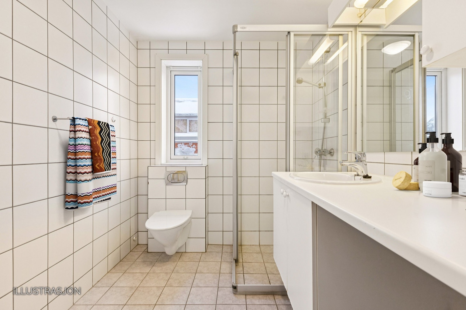 Helfliset bad utstyrt med vegghengt toalett, servantinnredning, dusjhørne og opplegg for vaskemaskin. Galleribilde