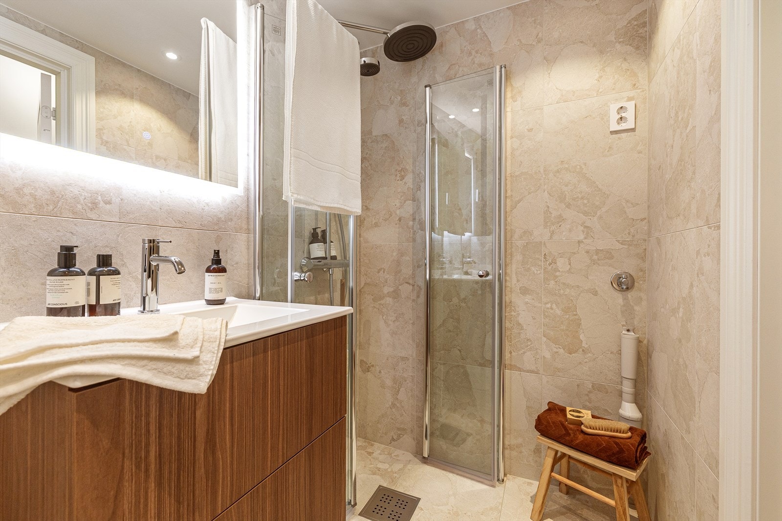 Innredning bestående av vegghengt toalett, servant med skuffer og dusjhjørne med glassdør. Det er opplegg for vaskemaskin. Galleribilde