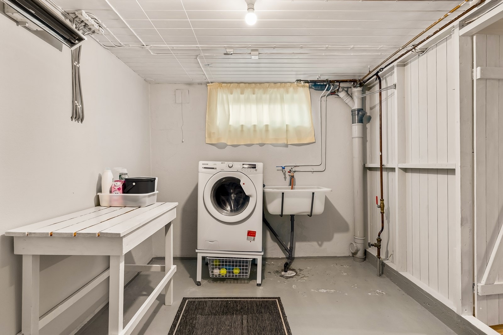 Praktisk vaskerom i kjelleren med betonggulv, opplegg for vaskemaskin og en varmtvannsbereder på ca. 200 liter. Galleribilde