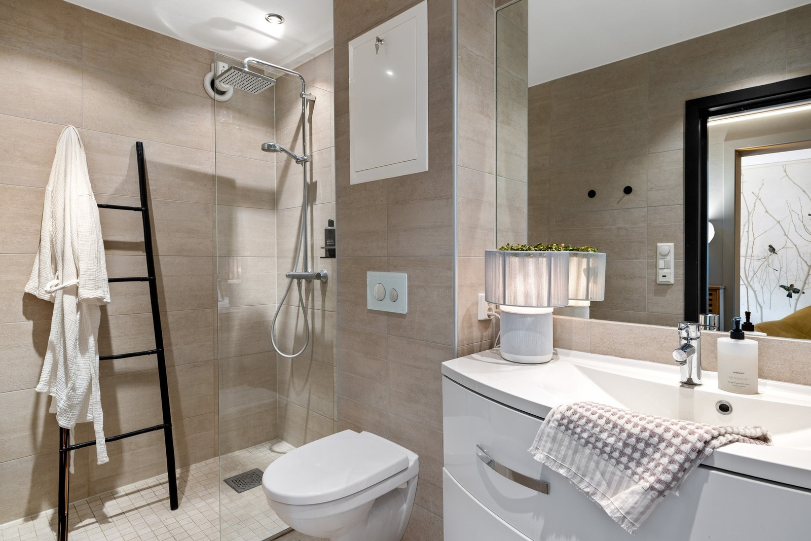 Badet i boligens 1.etasje har flislagt gulv med gulvvarme. Fliser på vegg og malte overflater i taket med downlights. Galleribilde