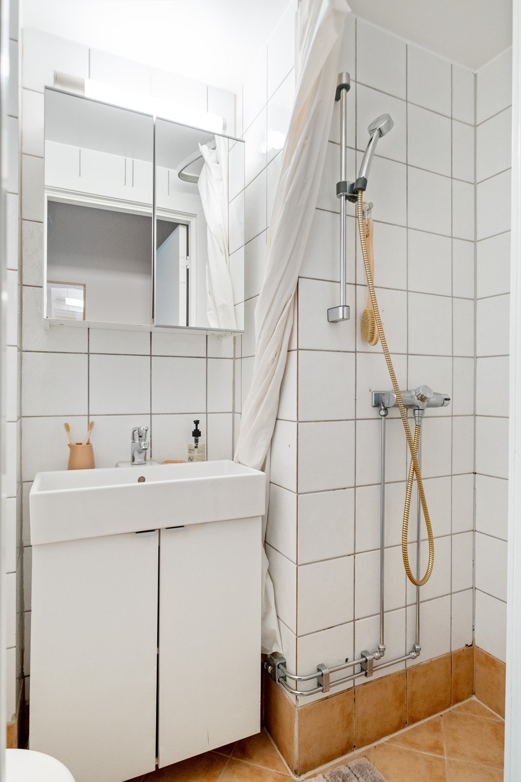 Flislagt bad med wc, dusj, servantinnredning med skap og speilskap. Galleribilde