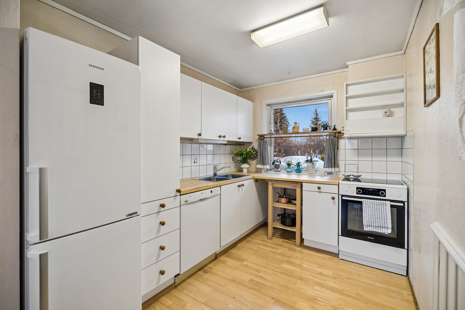 Kjøkkeninnredning med glatte fronter og laminat benkeplate. Kjøkkenventilator med avtrekk ut. Galleribilde