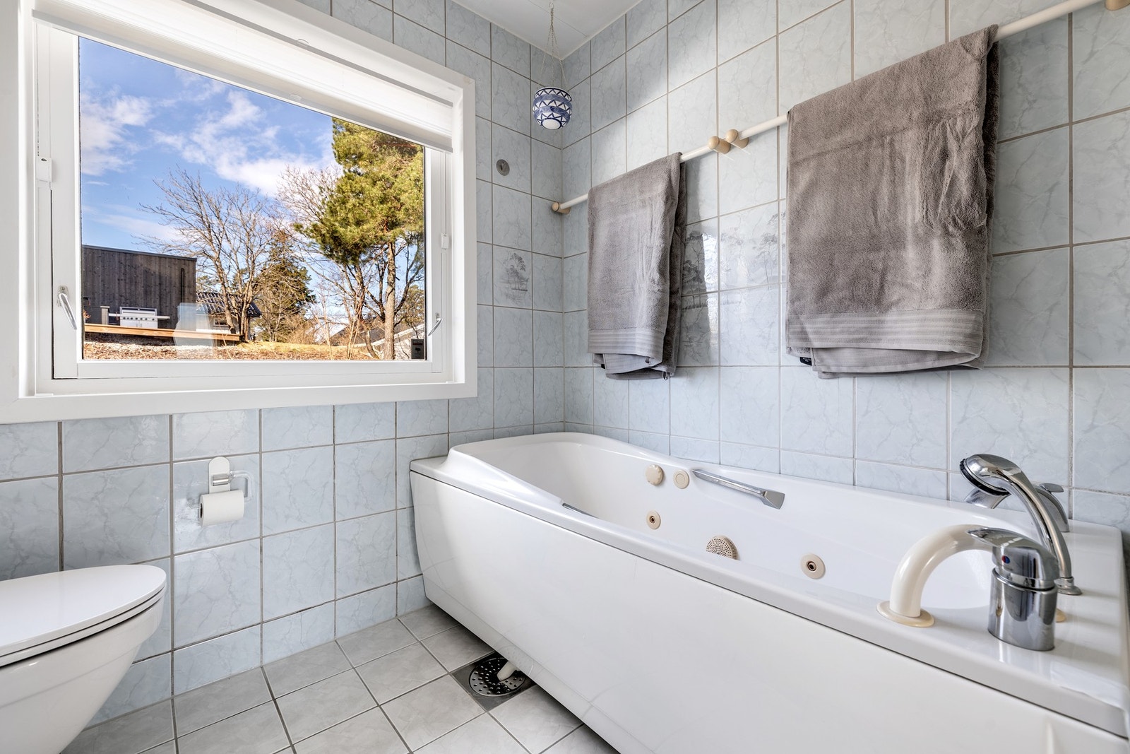 Badet i første etasje er utstyrt med flislagte vegger og gulv. Badet er innredet med to nedfelte servanter på skapseksjon, speil med overskap og belysning, frittstående toalett, badekar (med boblebad funksjon) og dusjhjørne. Galleribilde
