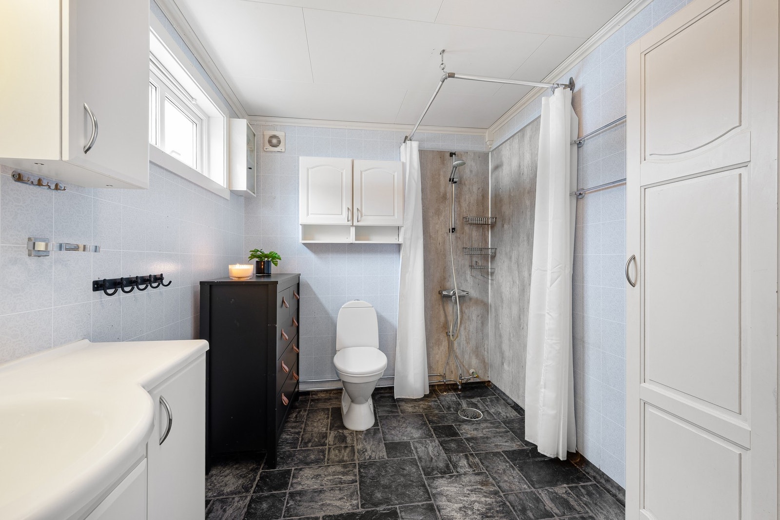 Badet inneholder servantinnredning, oppbevaringsplass, dusjnisje og toalett Galleribilde