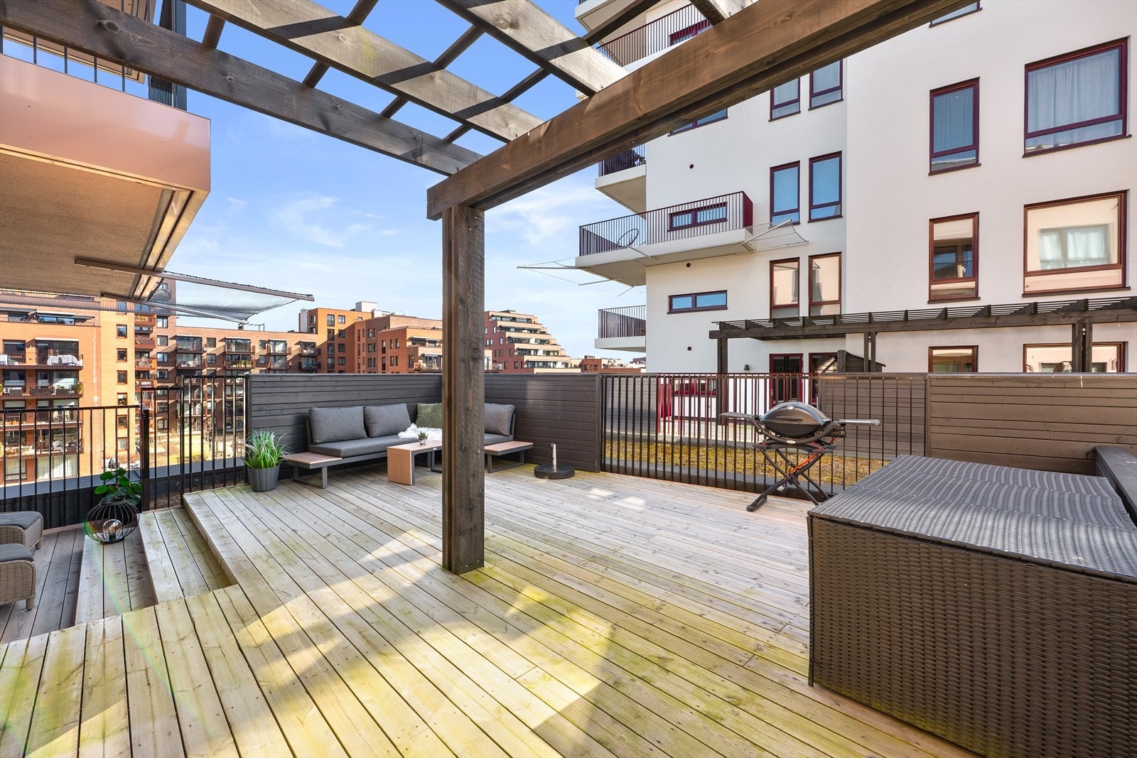 En pergola i tre rammer inn en del av uteplassen og gir en lun atmosfære. Galleribilde