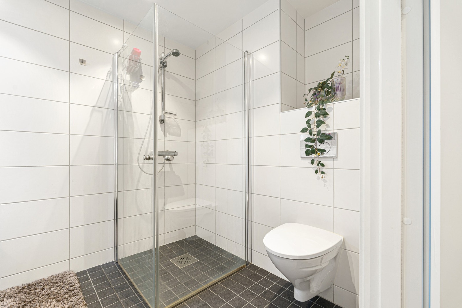 Badet byr på opplegg for vaskemaskin og har en praktisk hjørnedusj med innfellbare dører som kan ryddes bort for bedre plass. Galleribilde