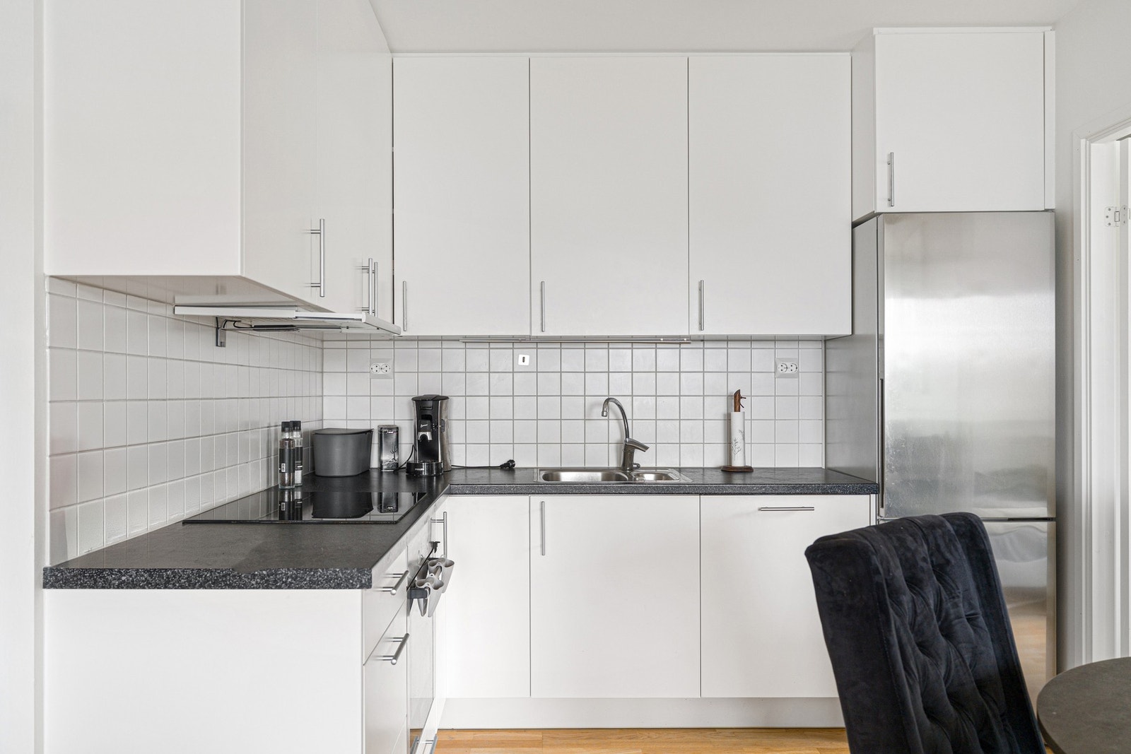 Stilrent kjøkken med integrerte hvitevarer som platetopp, stekeovn og oppvaskmaskin. Galleribilde