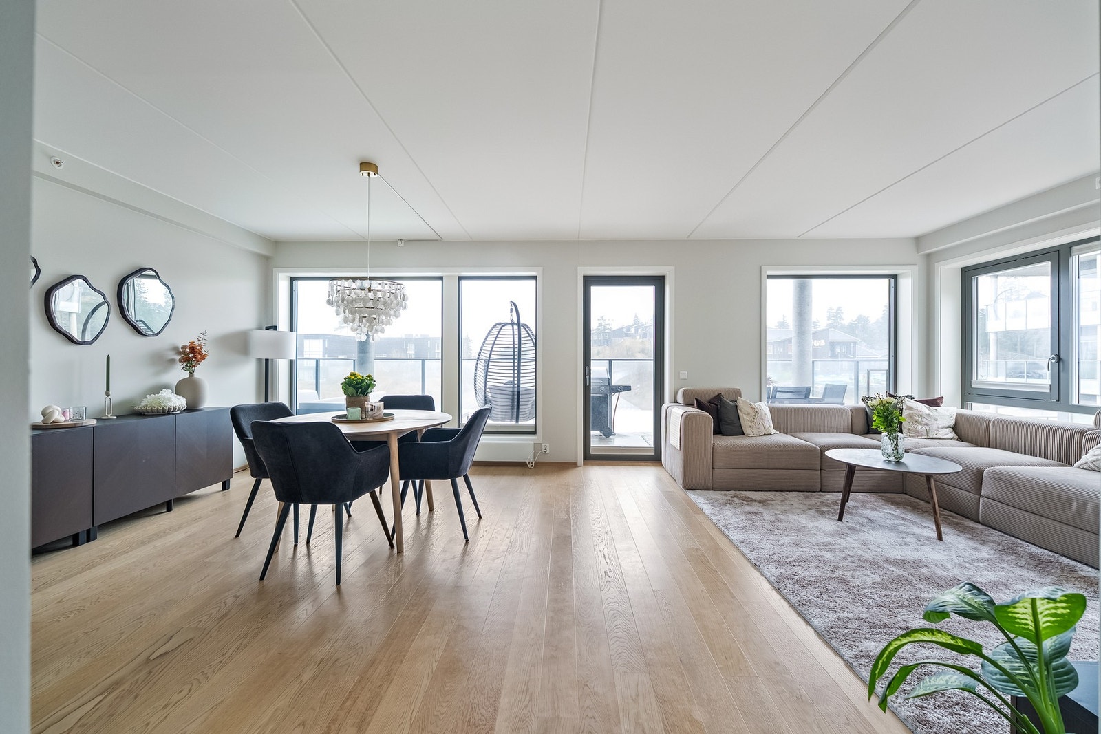 Åpen stue med store vindusflater fra gulv til tak i flere himmelretninger, som slipper inn rikelig med naturlig lys. Galleribilde
