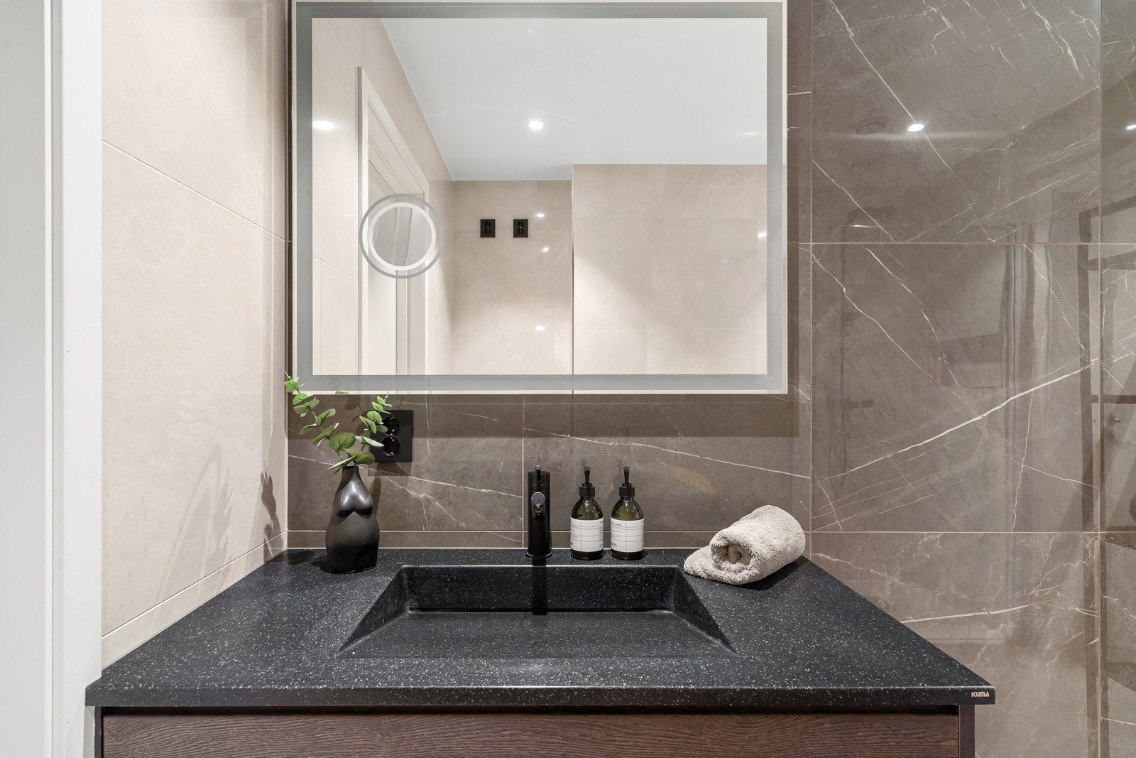 Nedfelt servant i mørk utførelse og overspeil med belysning.