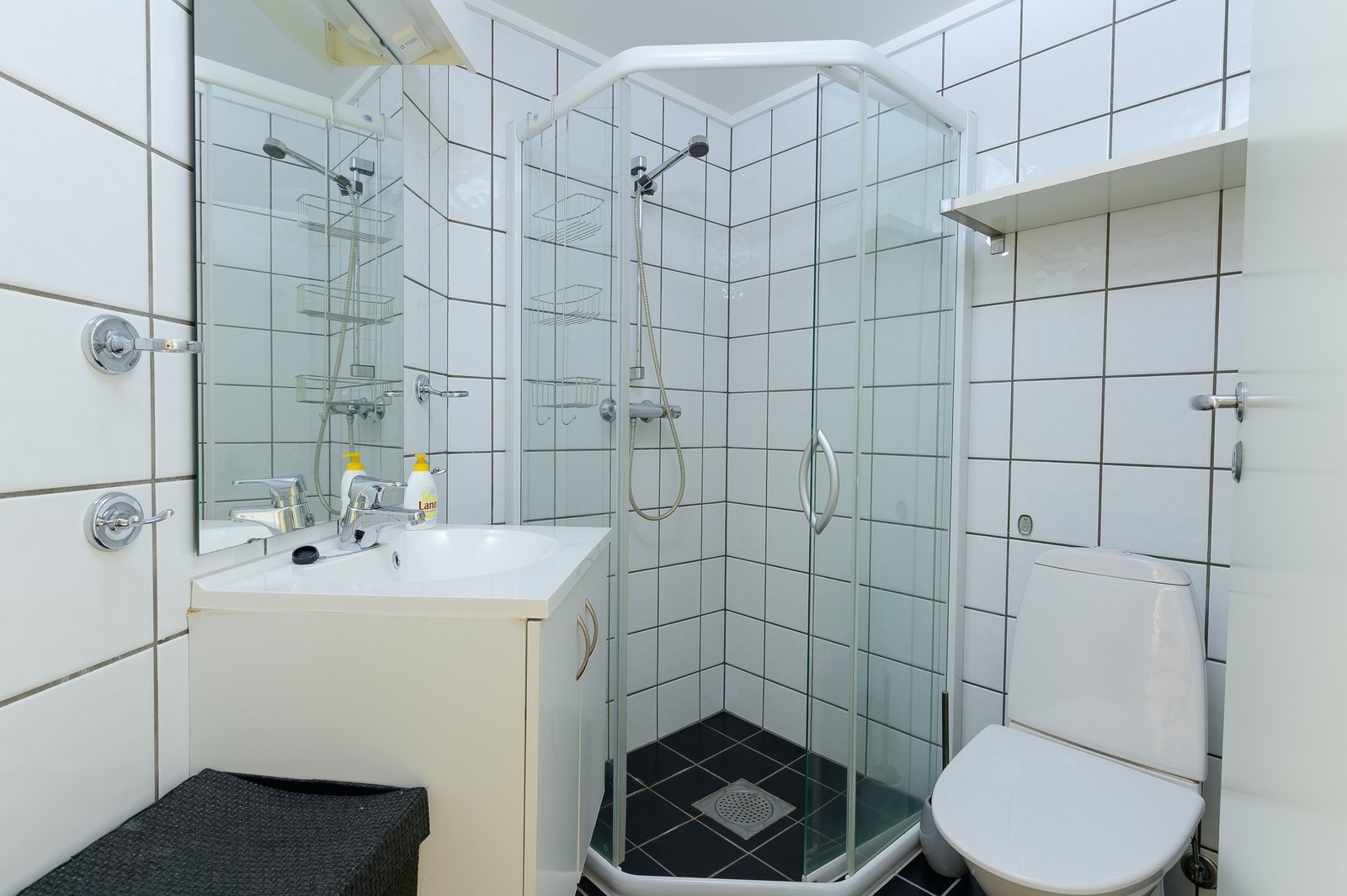 Flislagt bad med hvit baderomsinnredning og vaskemaskin. Galleribilde
