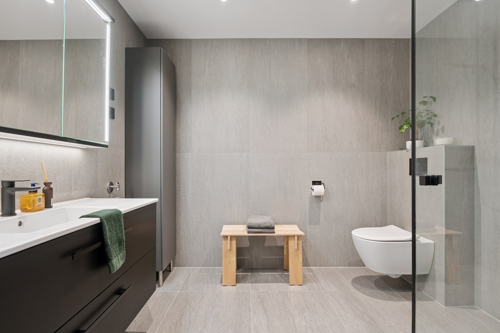 Romslig og helfliset bad med vegghengt toalett og moderne innredning. Galleribilde