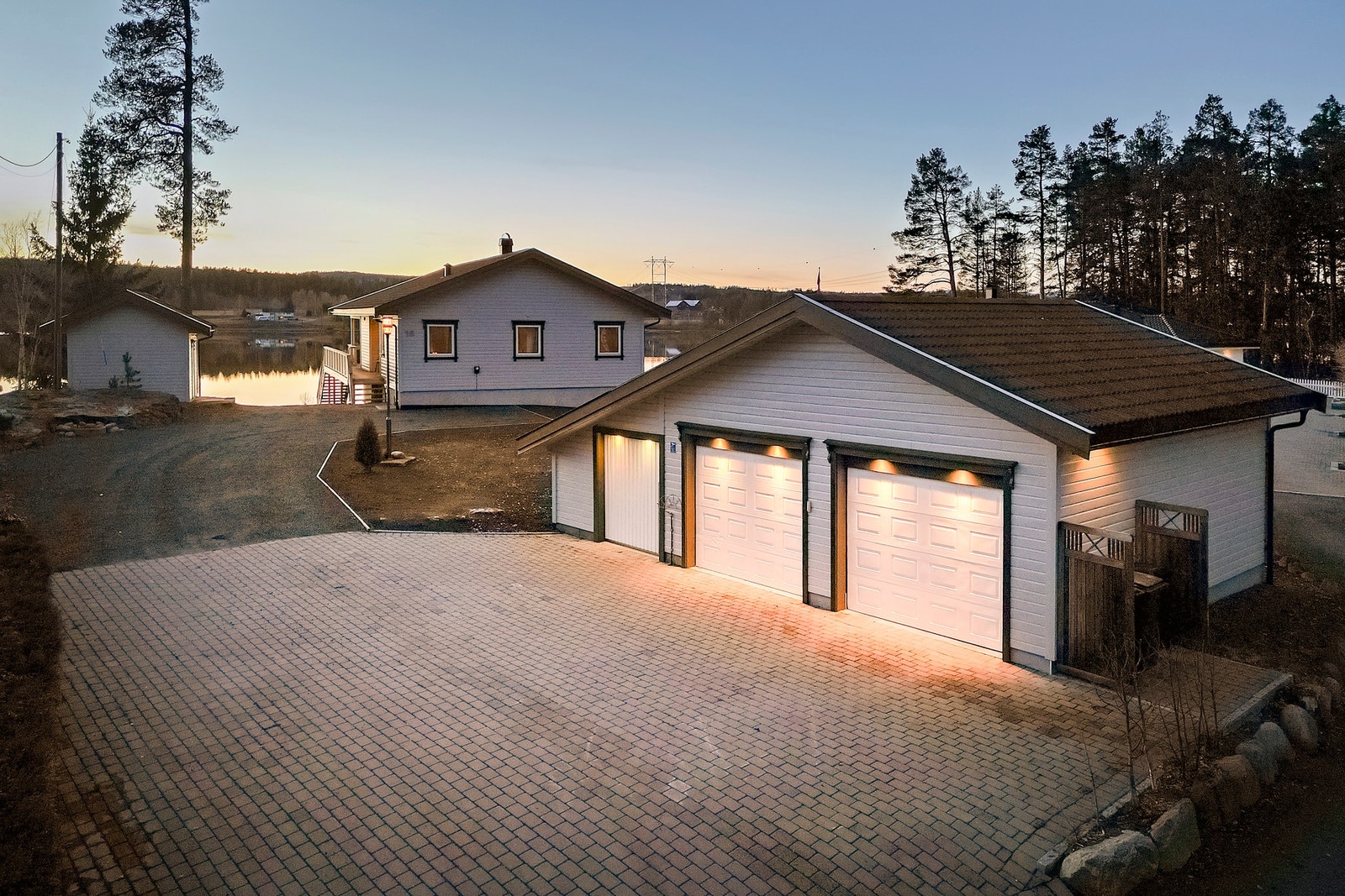 Stor dobbelt garasje. Brosteinsbelagt gårdsplass.
Kveldsstemning. Galleribilde