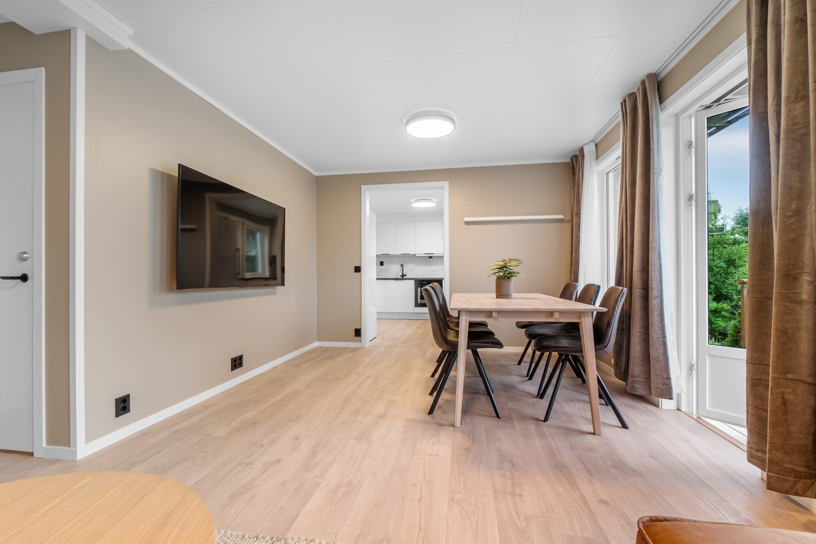 Spisegruppe og vegghengt 65" SmartTV. Det er også robotstøvsuger i stuen. Galleribilde