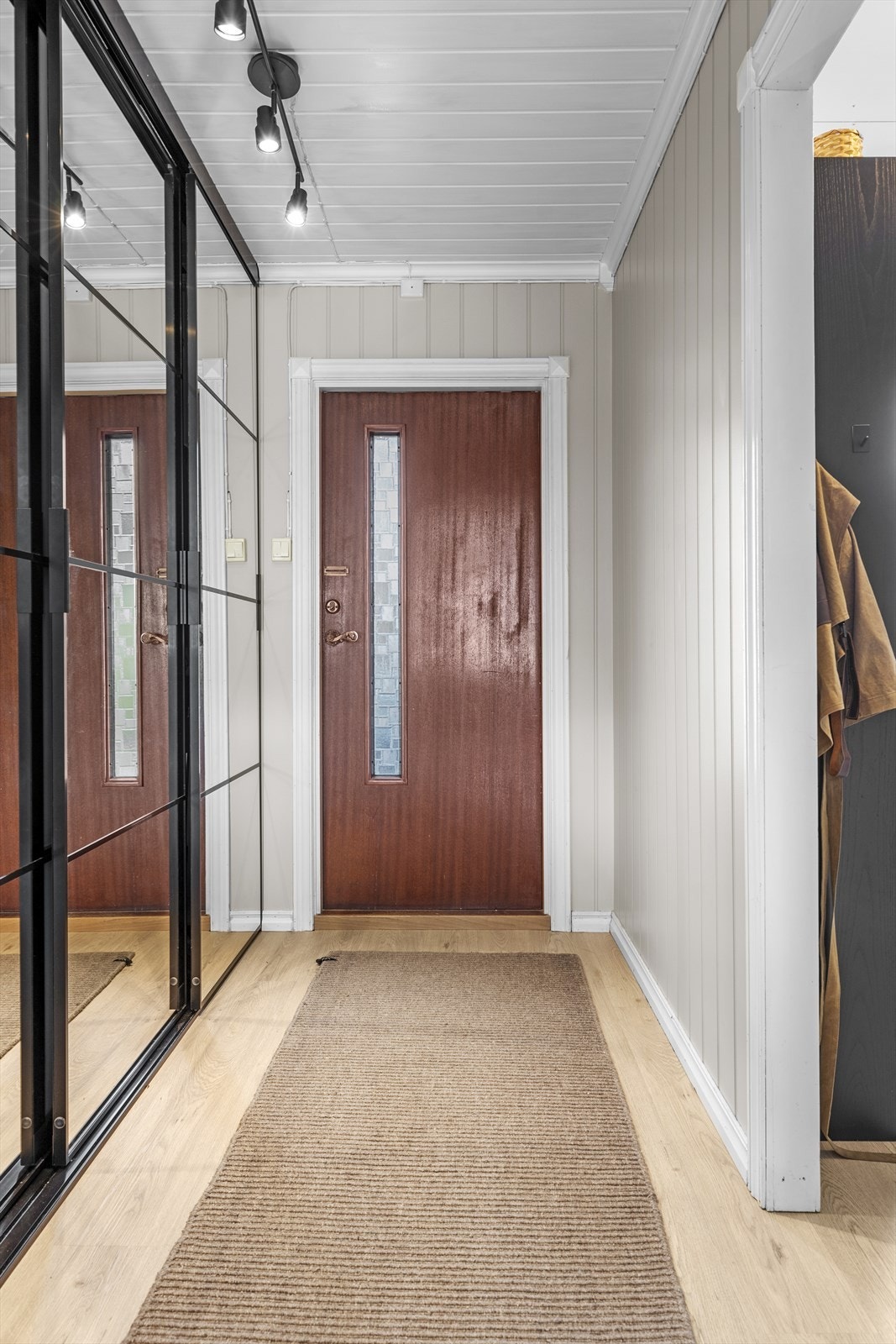 Fra overbygd inngangsparti, trer du inn i lys entré - velkommen inn! Her er det romslig skyvedørsgarderobe med speilfronter som medfølger i salget Galleribilde