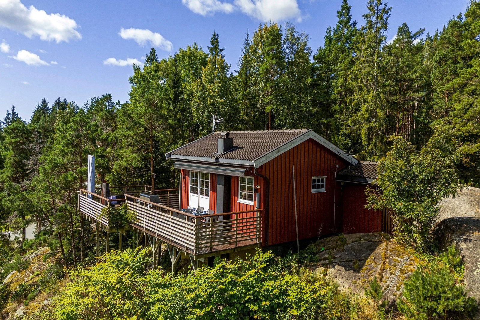 Hytte står på fjell. Terrassemarkise gir god skygge på solfylte dager. Galleribilde