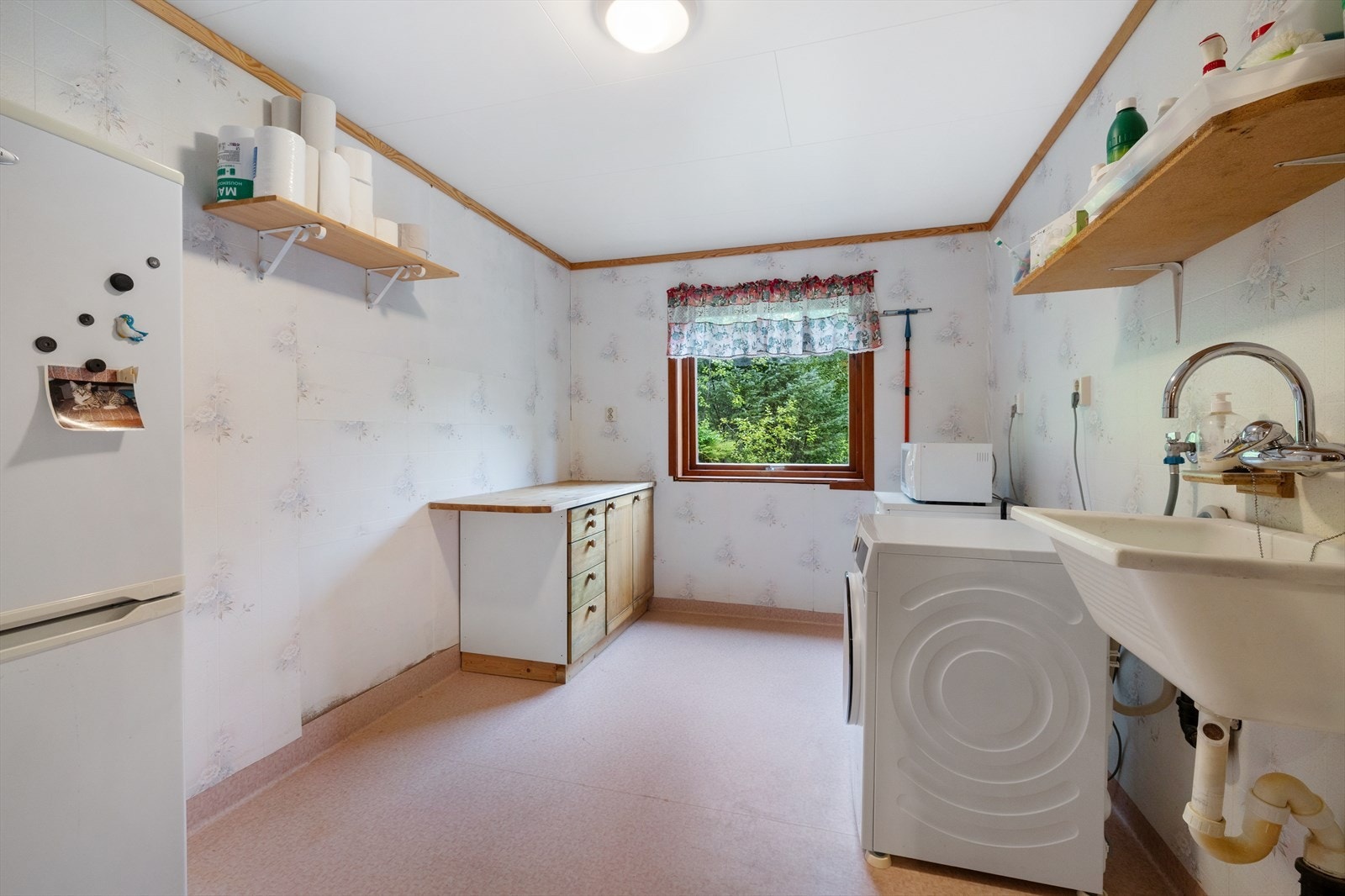 Vaskerommet er av eldre dato og har vinylbelegg på gulv og våtromsbelegg på vegger. Her er det opplegg for vaskemaskin og tørketrommel samt en utslagsvask i plast Galleribilde
