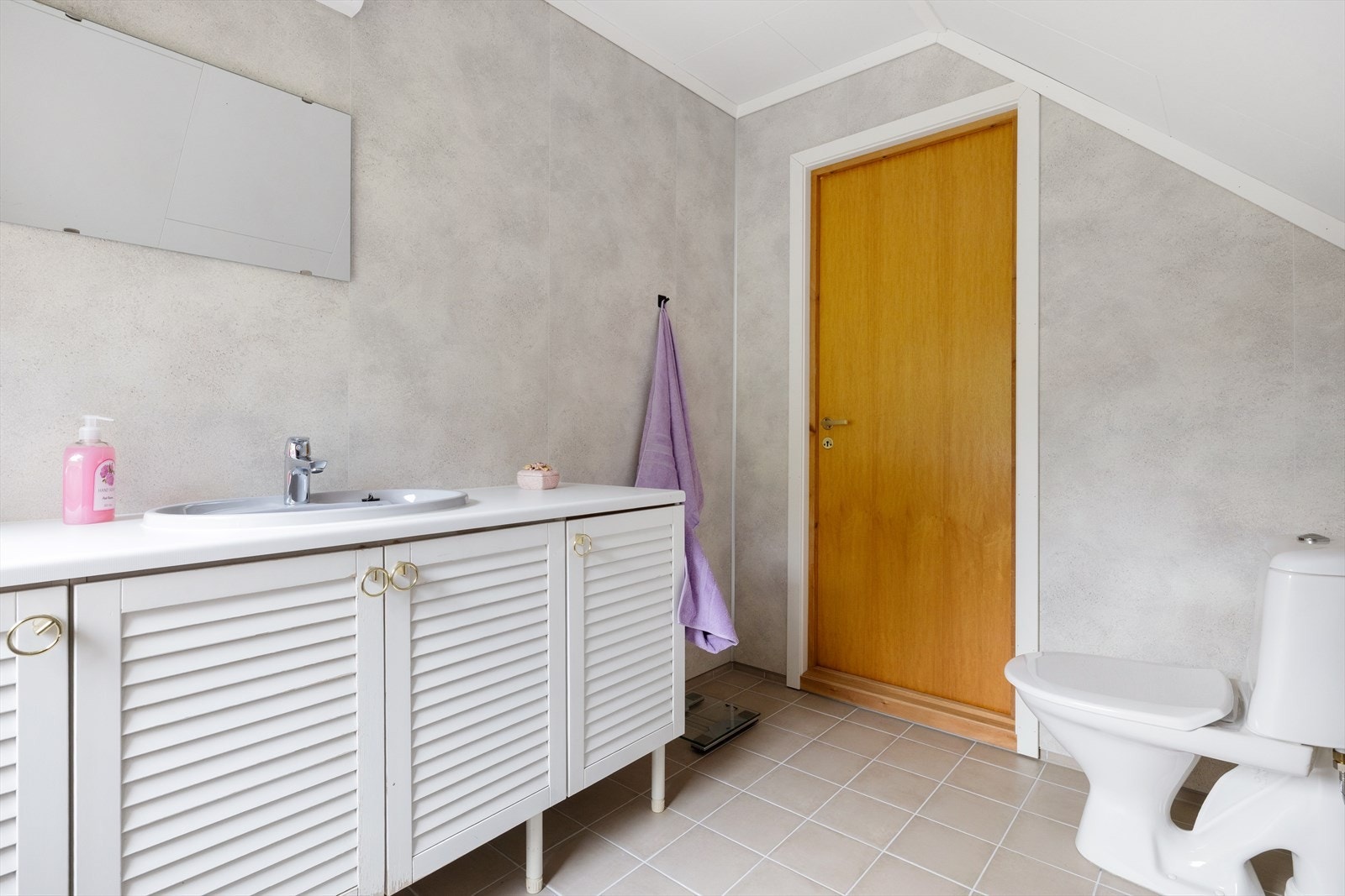 Badet er innredet med fliser på gulv og baderomsplater på veggene. Badet inneholder toalett, opplegg for dusj og servant med innredning Galleribilde