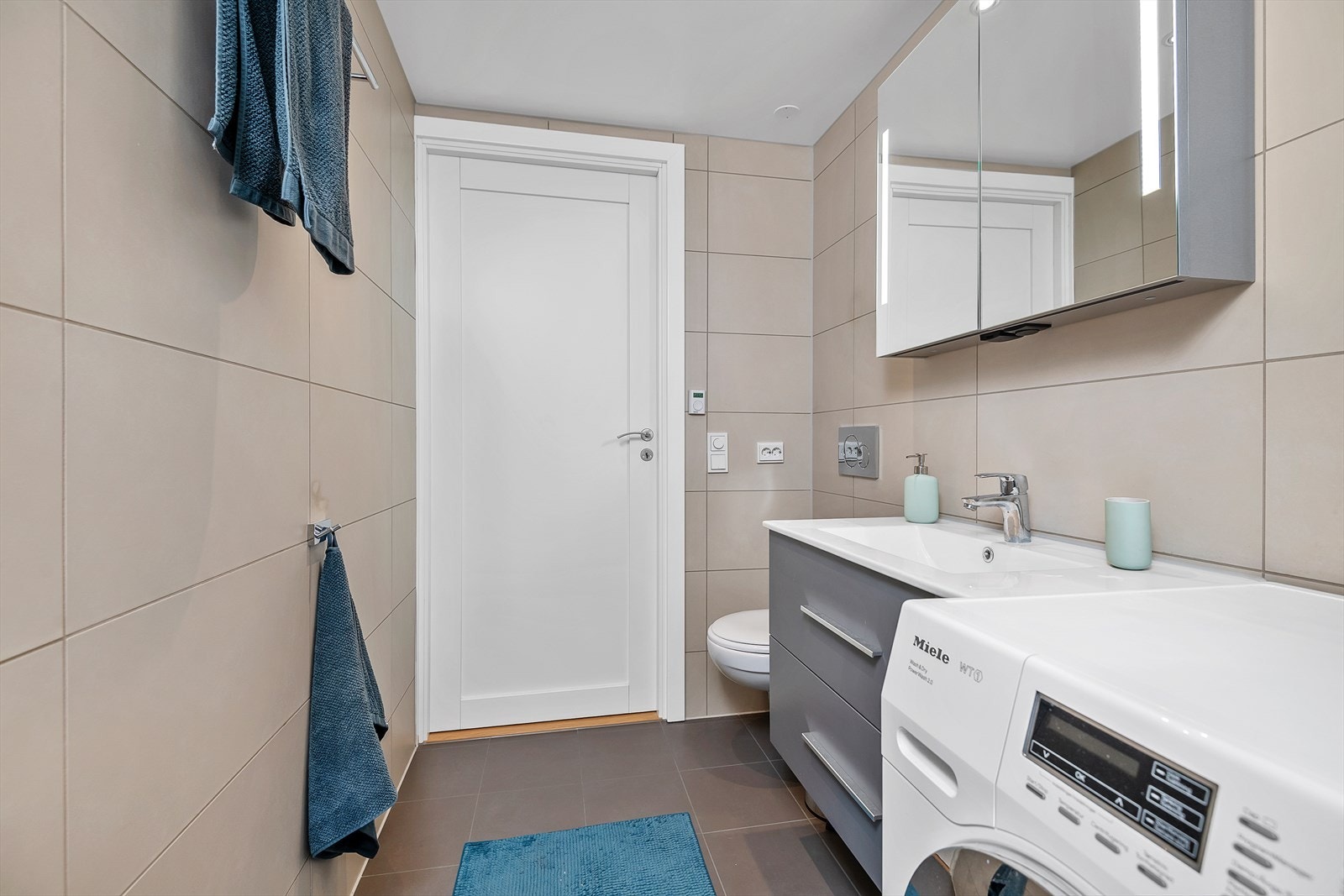 Det første badet har en fin og moderne utførelse. Her er det en moderne innredning med servant, speilskap med integrert belysning, vegghengt toalett og dusjhjørne med glassdør. Galleribilde