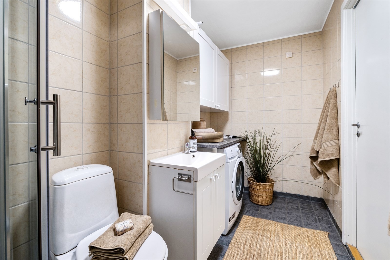 Badet er kombinert vaskerom og har flislagte overflater og elektrisk gulvvarme. Galleribilde