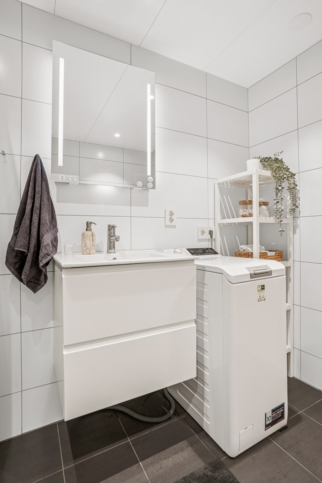 Innredet med en heldekkende servant over en skuffeseksjon med glatte, folierte fronter, samt speil med integrert belysning. Galleribilde