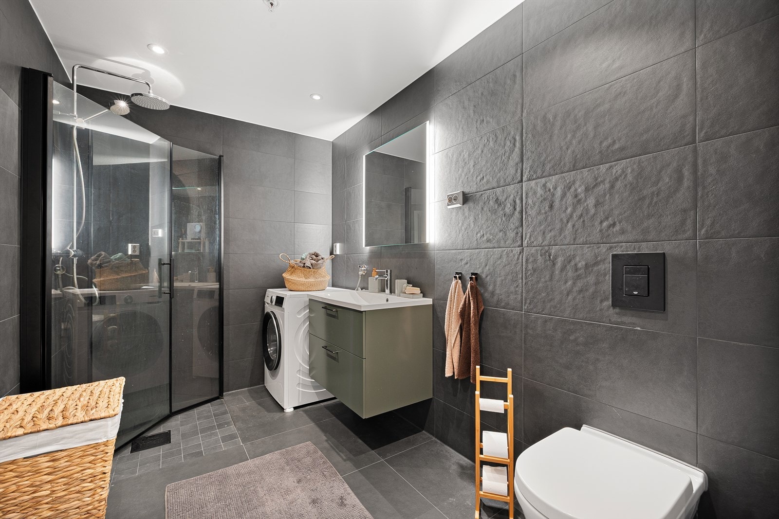 Badet er stilrent utformet med mørke fliser som gir et eksklusivt og moderne uttrykk. Galleribilde