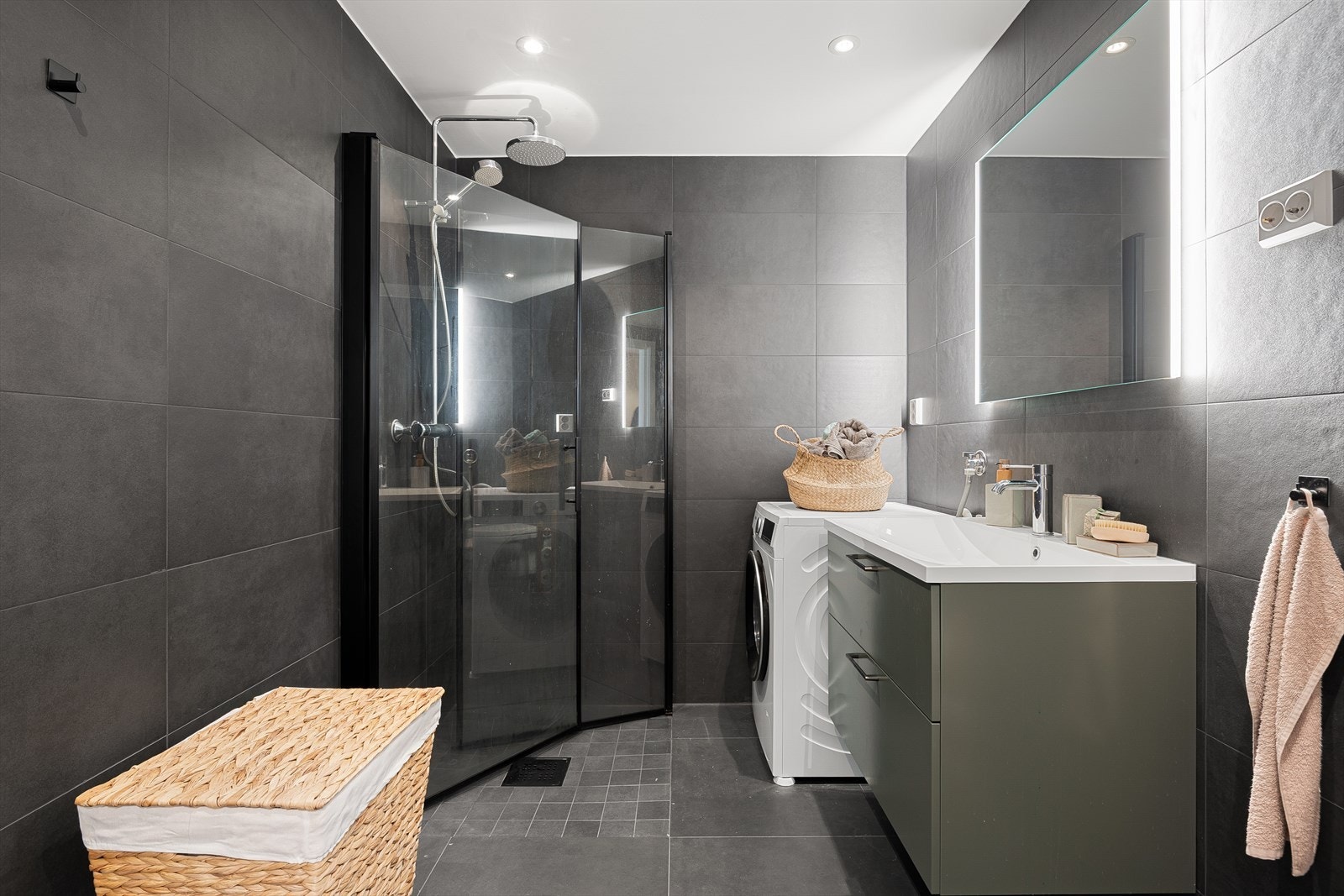 Lekre detaljer i sort og mørkegrønt skaper en gjennomført helhet, og badet er samtidig praktisk med skap under servant og opplegg for vaskemaskin. Galleribilde
