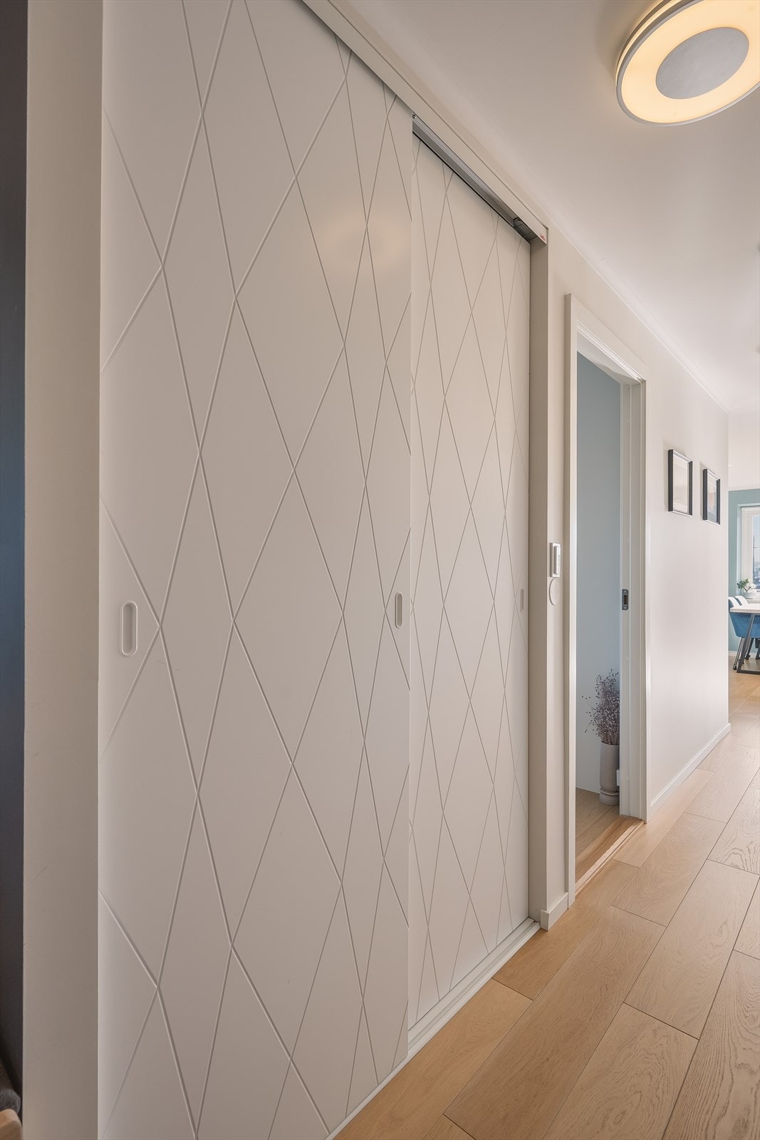 Garderobeløsningen med skyvedører og profilerte fronter sørger for praktisk og ryddig oppbevaring i entrè. Galleribilde